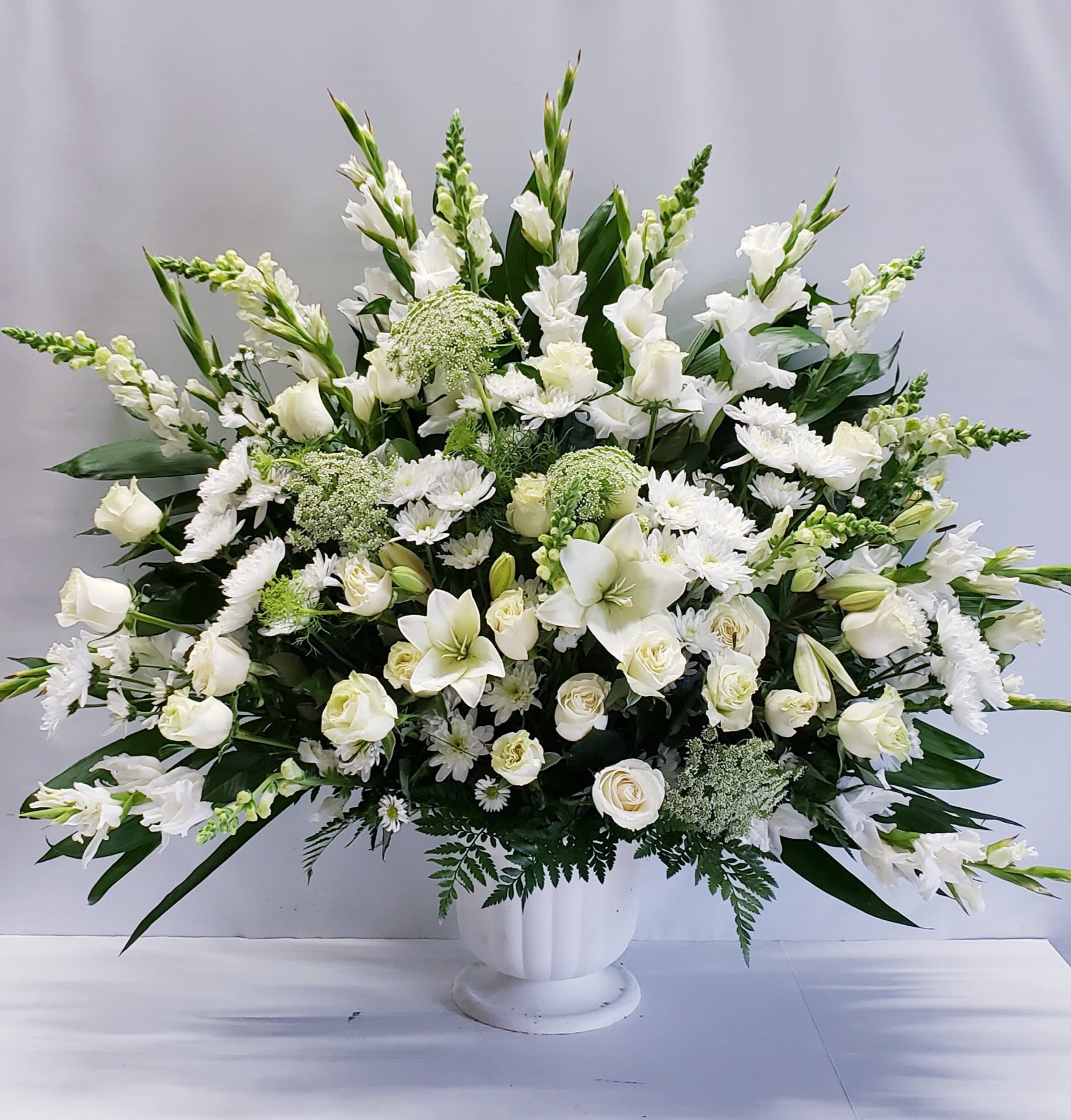 Large white floral arrangement in a white pedestal vase