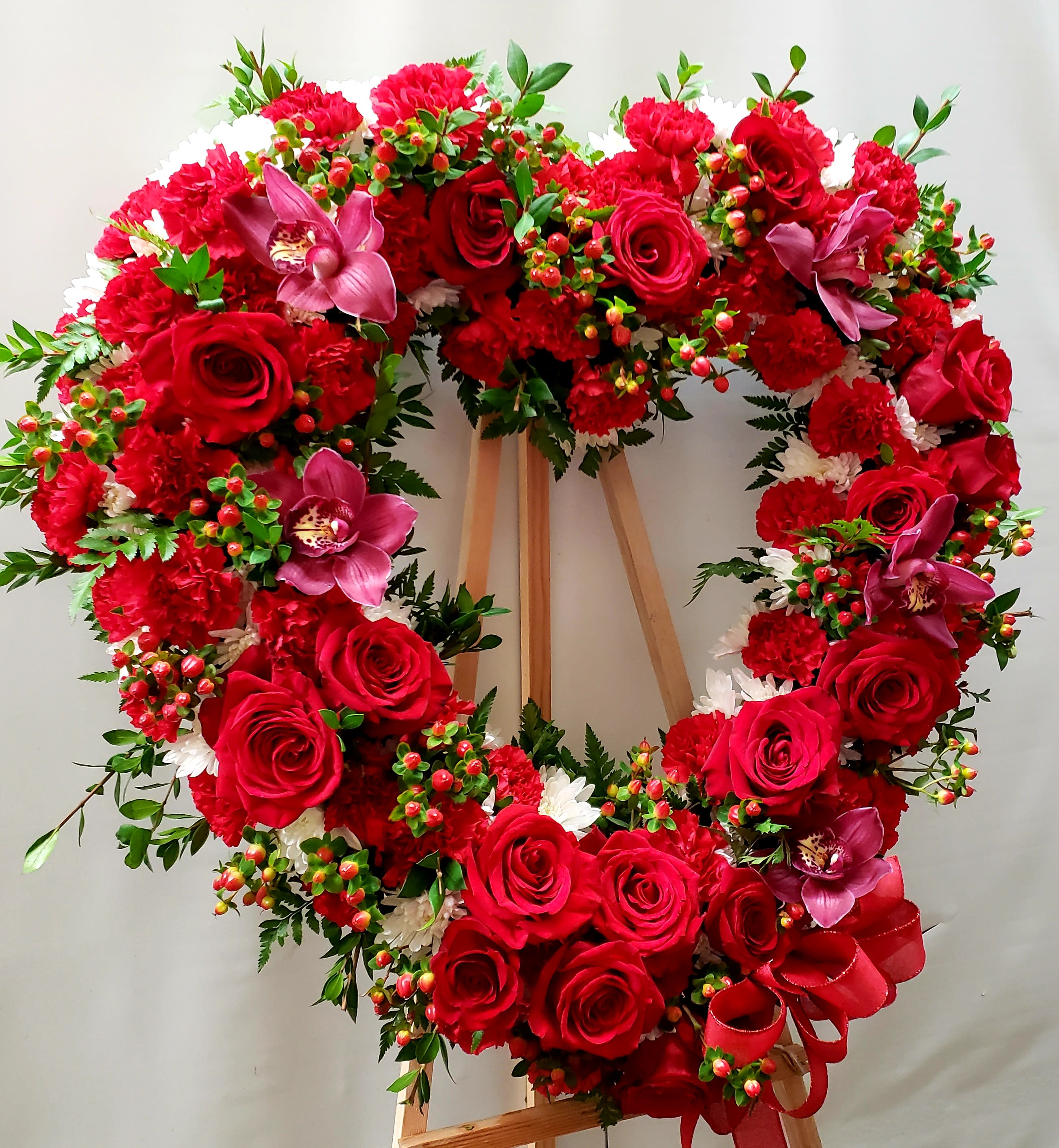 Heart-shaped wreath of red roses and carnations with pink orchids