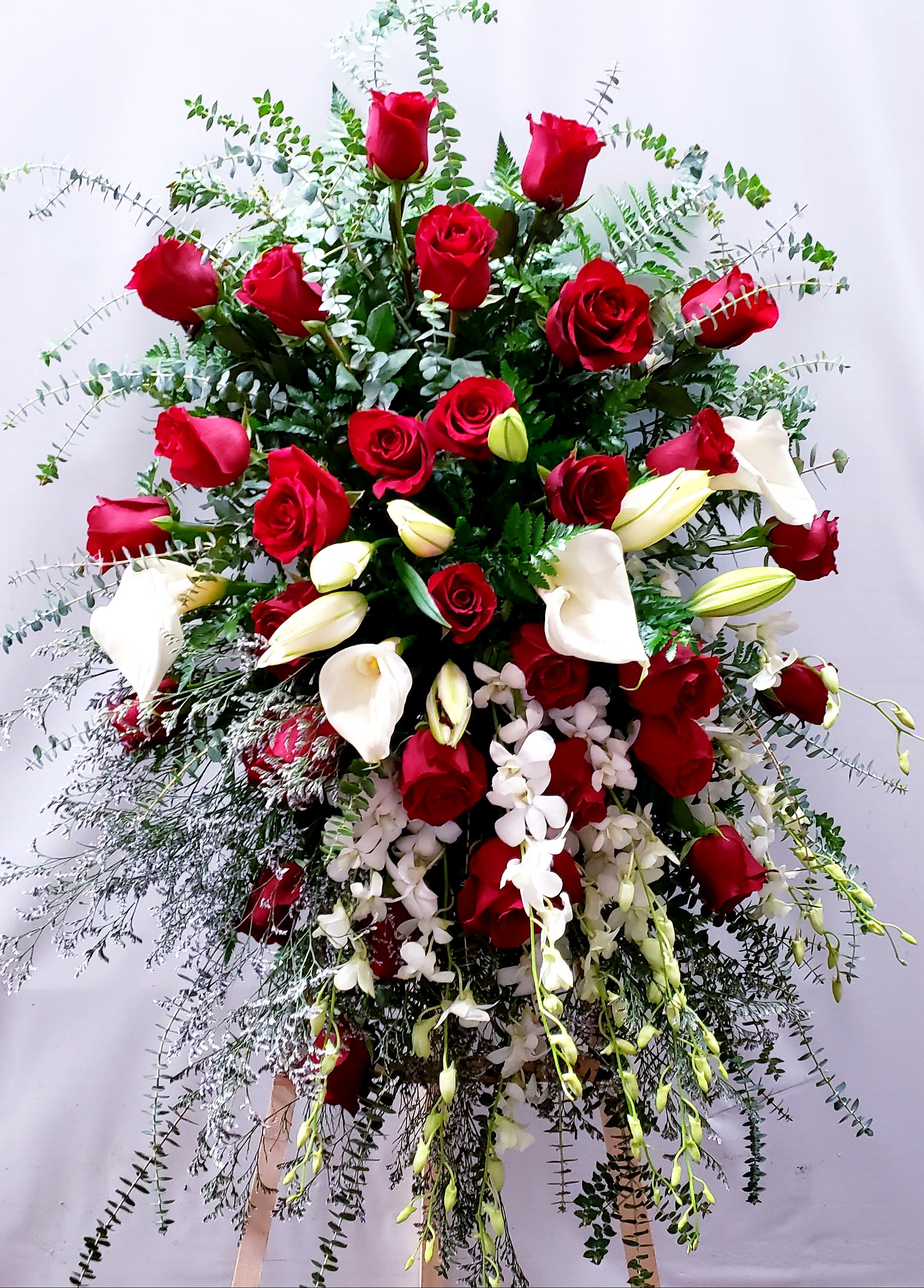 Large standing arrangement of red roses and white calla lilies