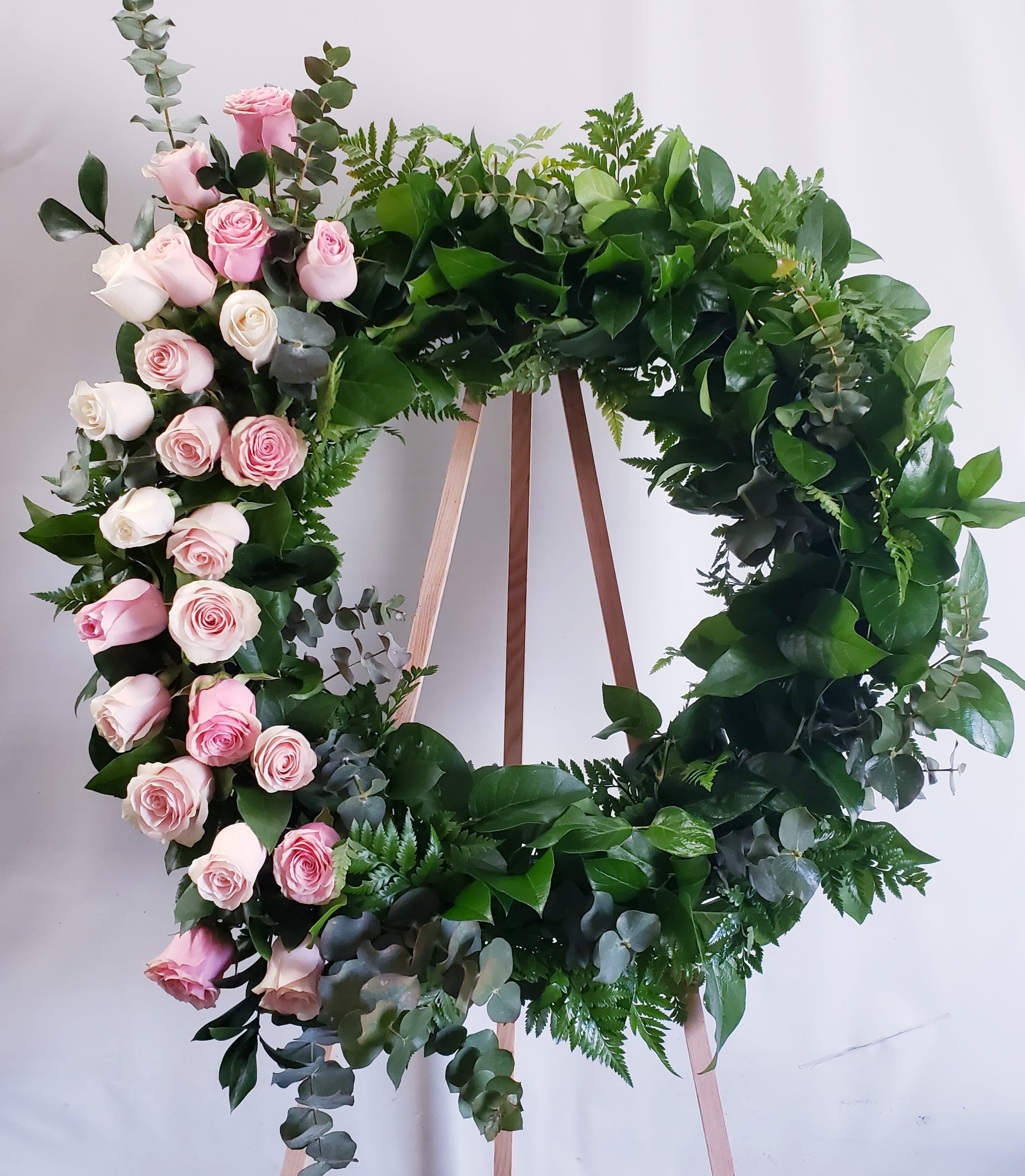 Circular wreath of pink and white roses on a wooden stand