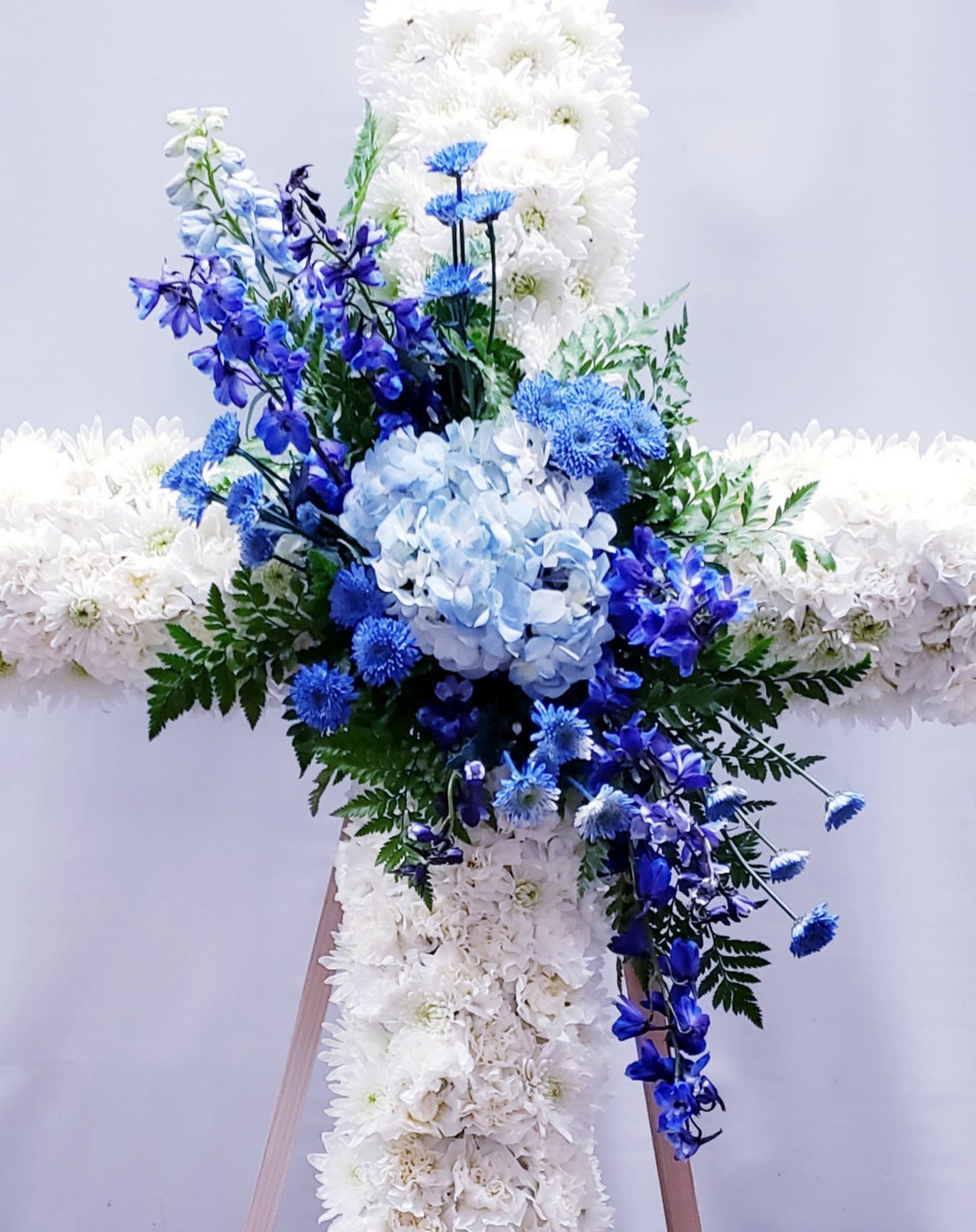 Blue and white floral cross arrangement on a stand