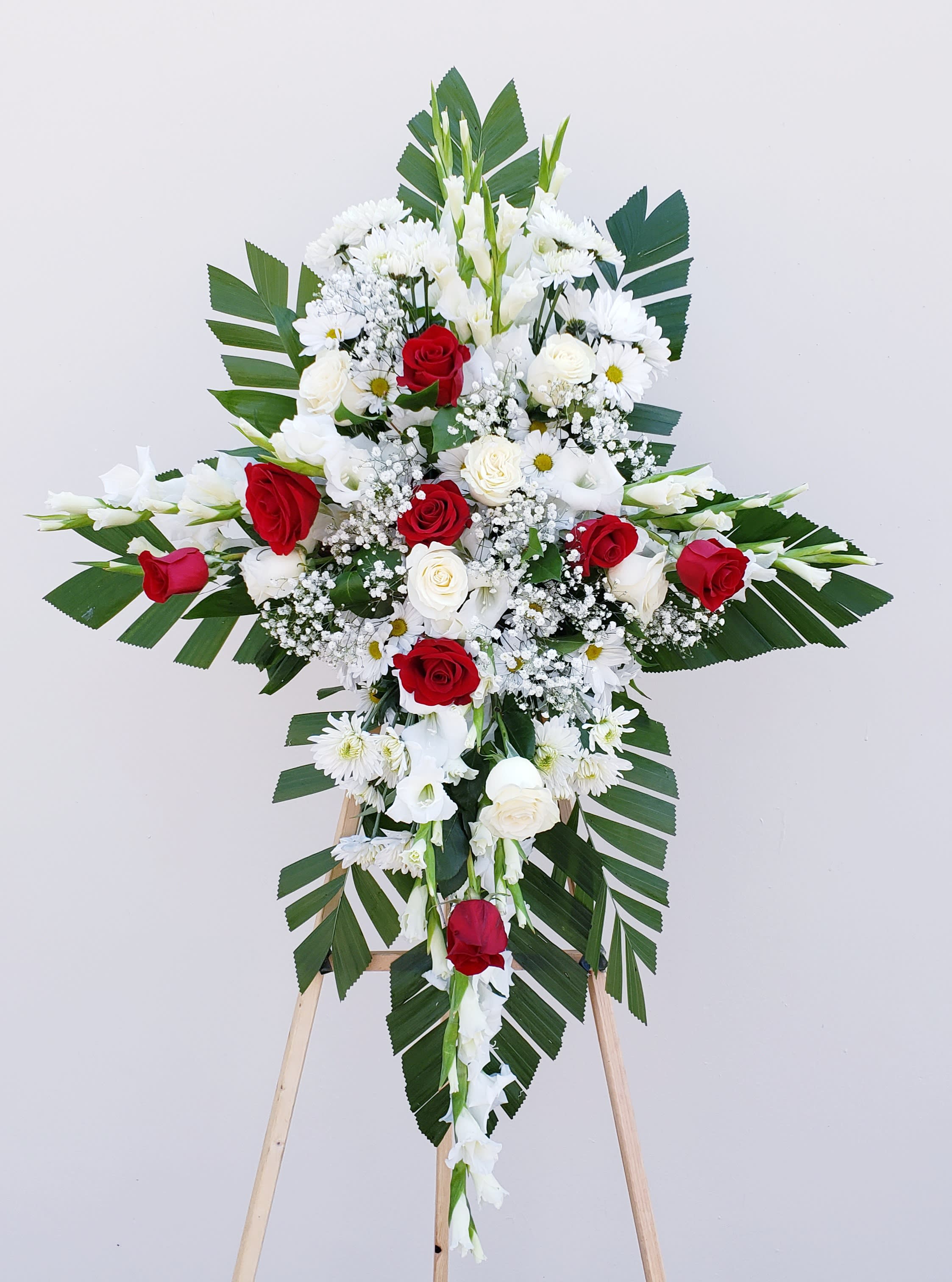 Standing floral cross with red and white roses and daisies