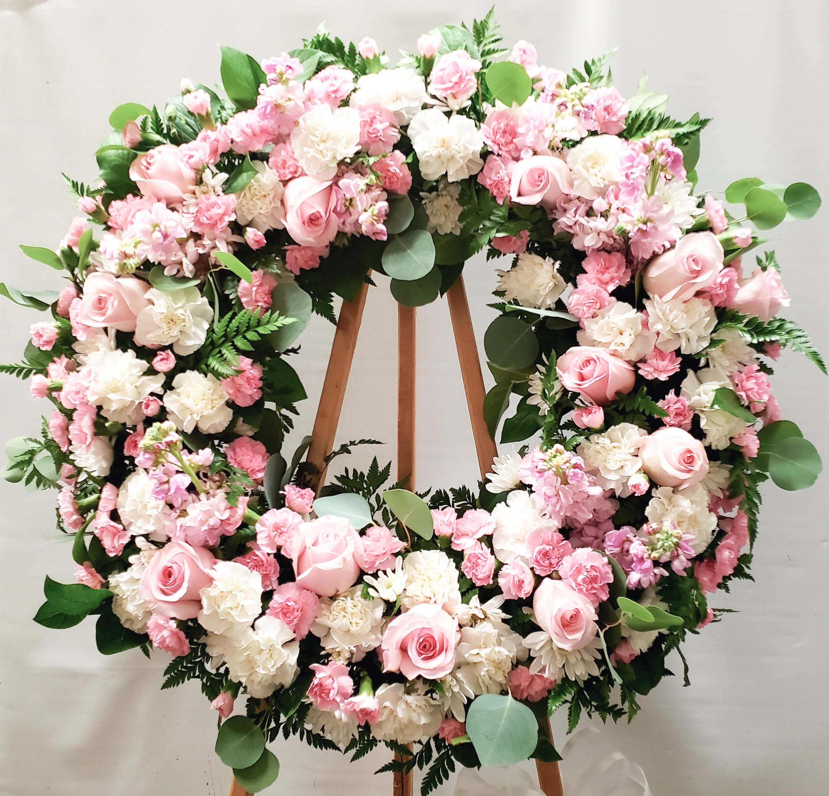 Large pink and white floral wreath on a wooden stand