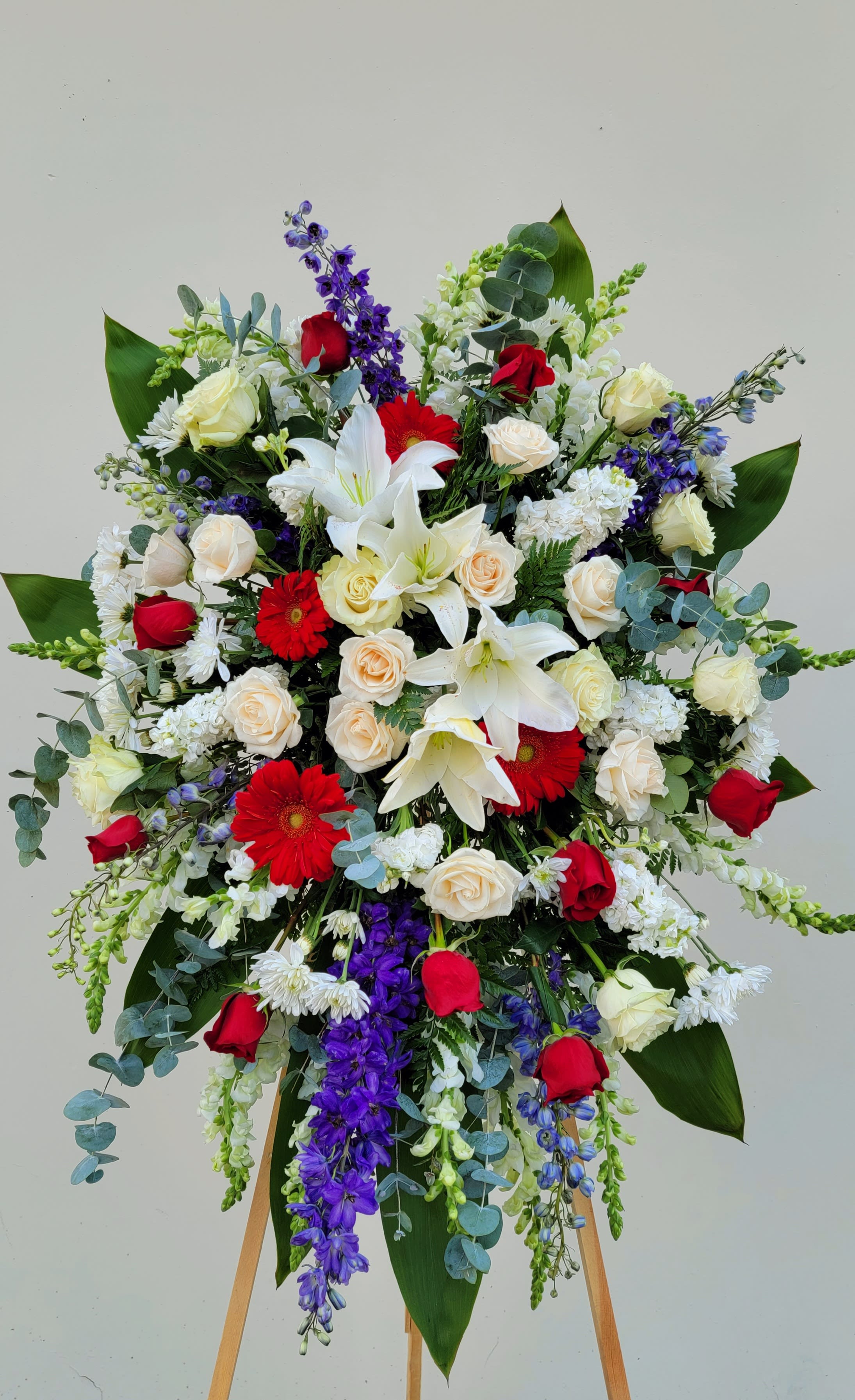 Large standing floral spray with red, white, and purple flowers on an easel