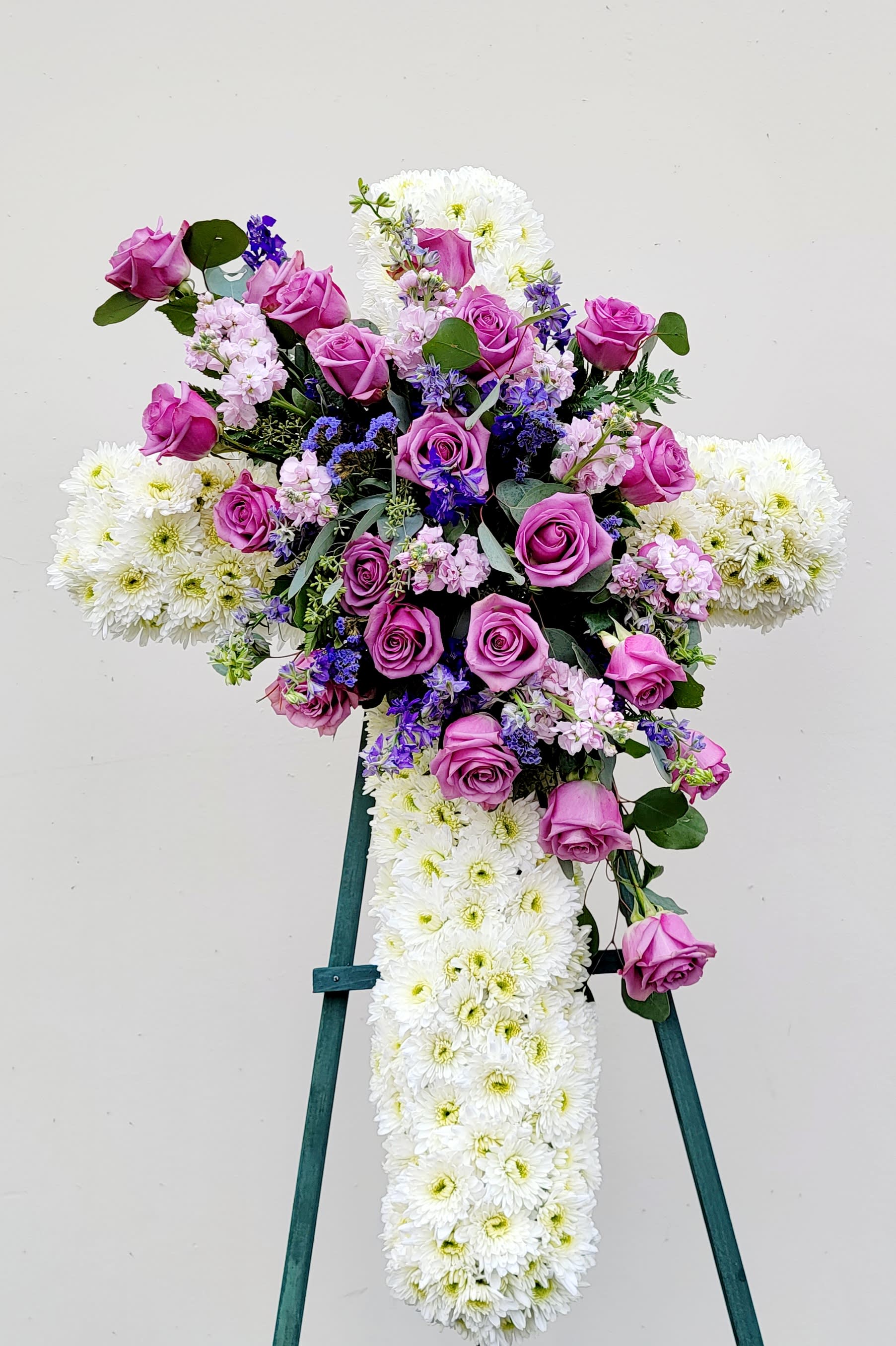 Cross-shaped floral spray with pink roses and white chrysanthemums on an easel