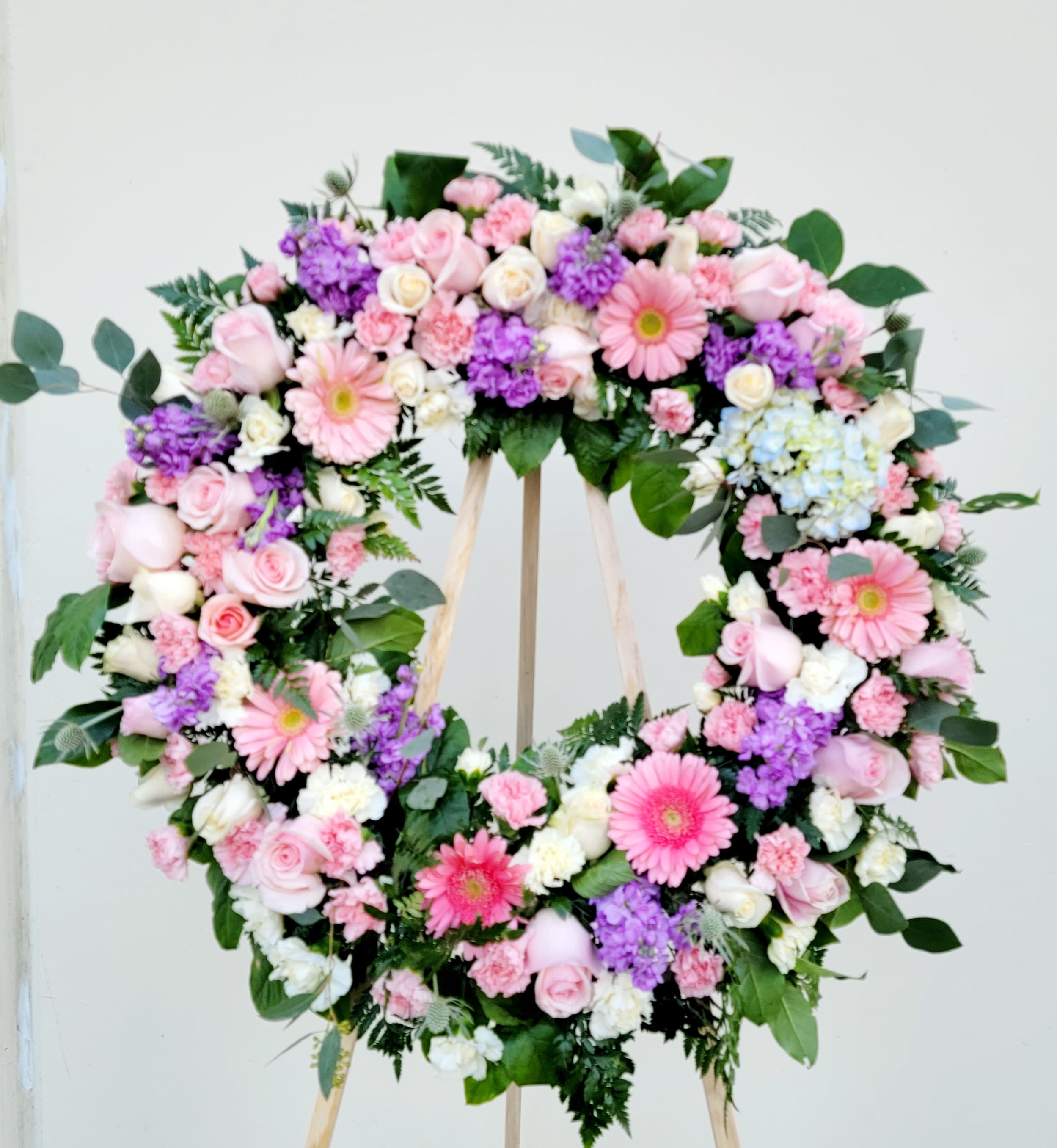 Heart-shaped floral wreath with pink, white, and purple flowers on an easel