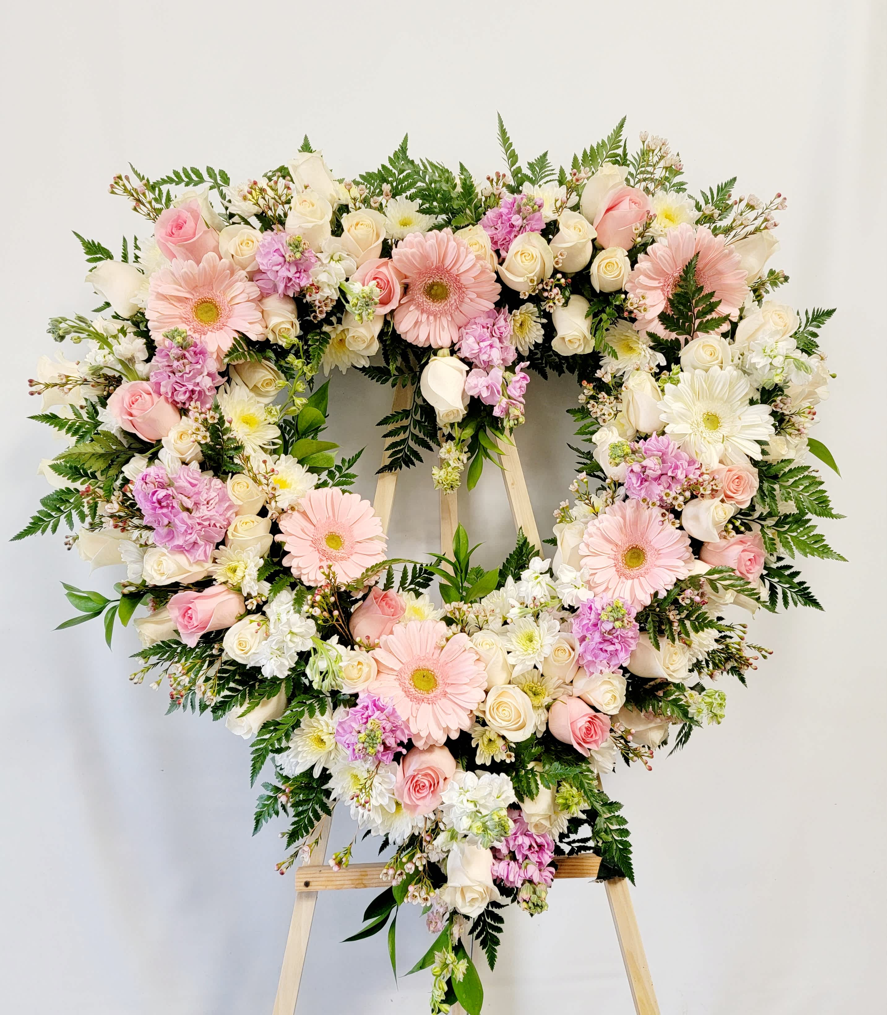 Heart-shaped floral wreath with pink and white flowers on an easel