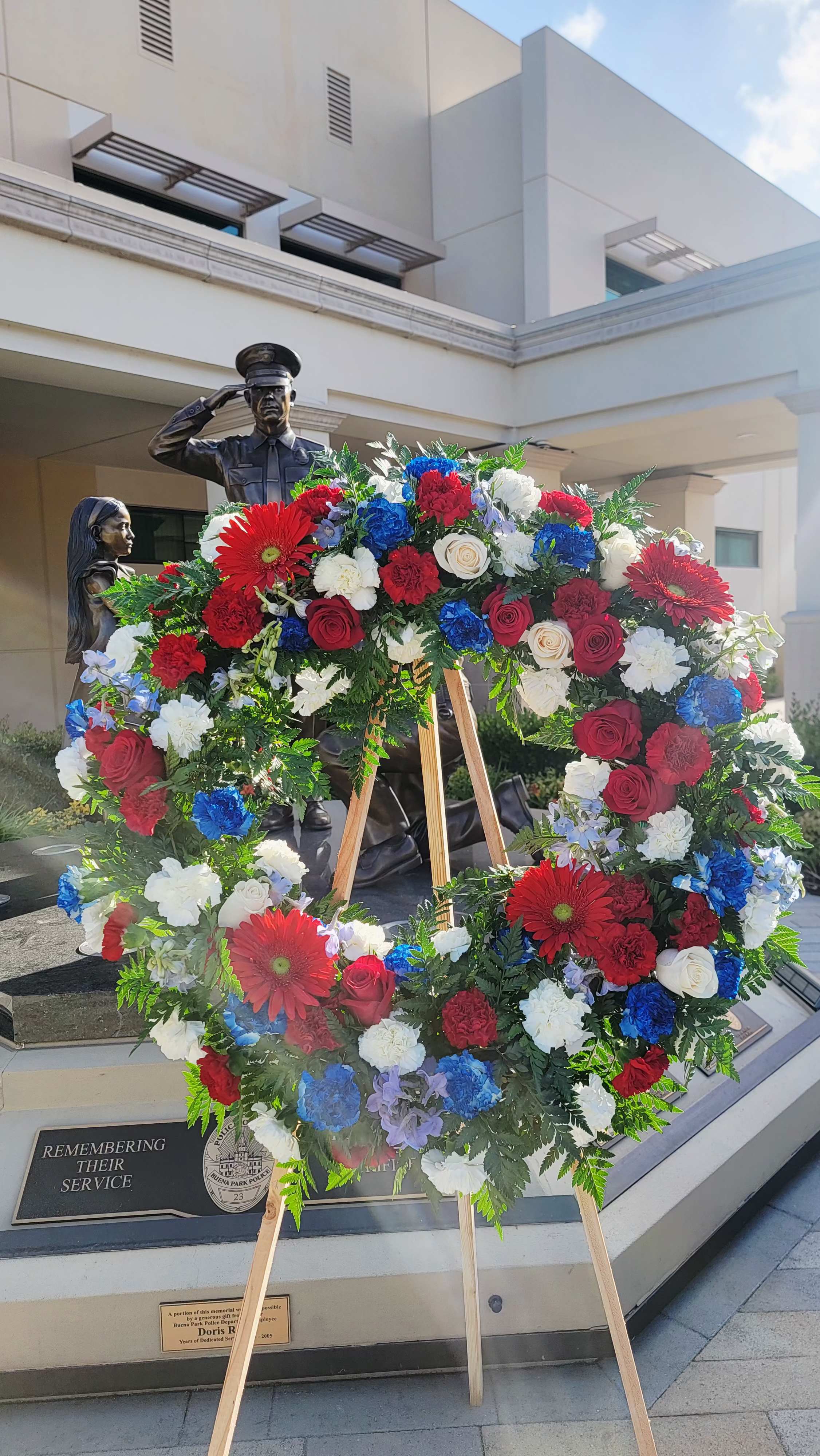 Large patriotic floral wreath on a wooden easel with red, white, and blue flowers