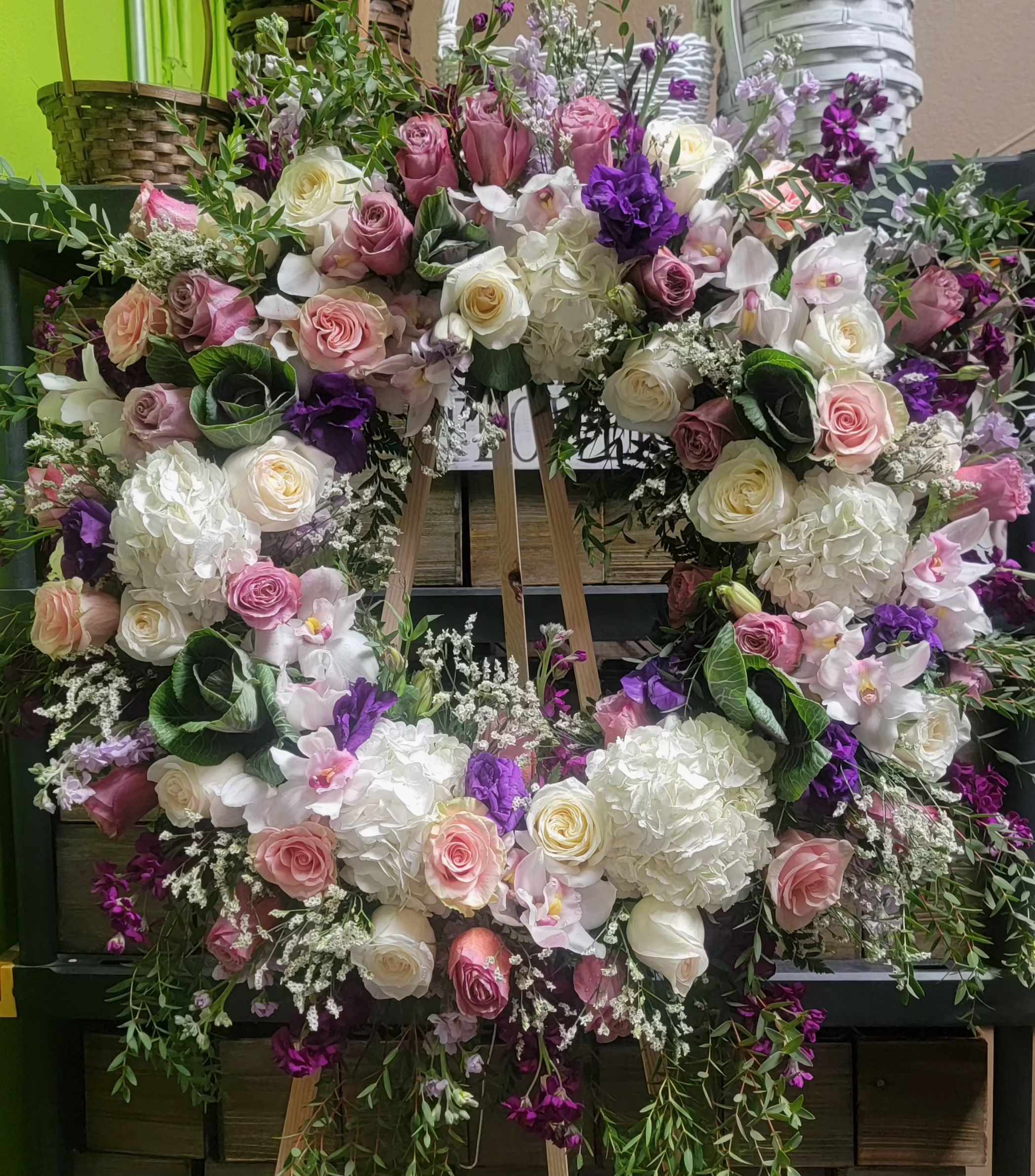 Large floral wreath with pink, white, and purple flowers on an easel