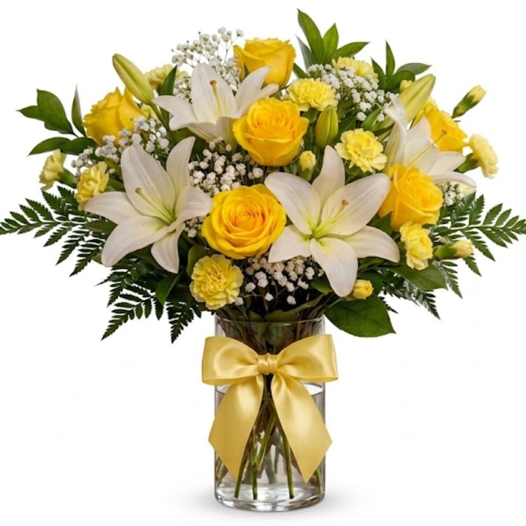Yellow roses and white lilies in a glass vase with a yellow ribbon
