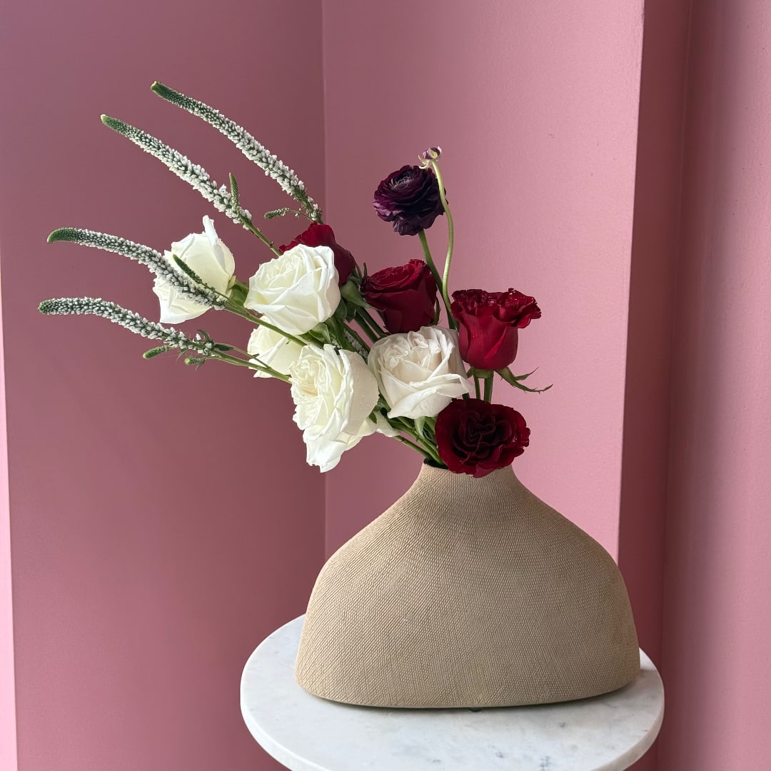 White and burgundy roses in a beige vase with tall white spikes