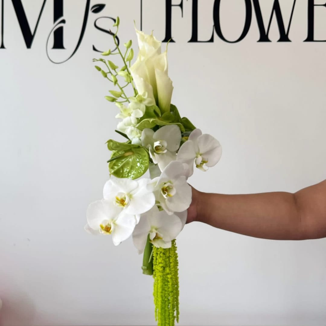 White orchid bouquet with green accents held in a hand