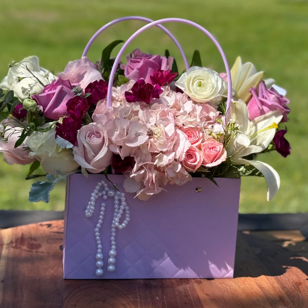 Pink and white flower arrangement in a lavender gift bag with pearl trim