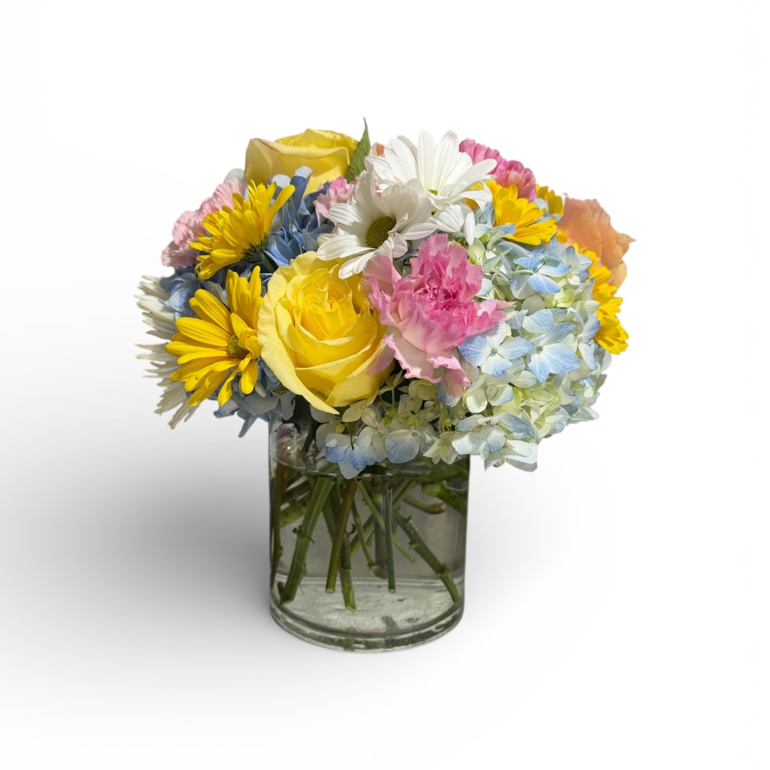 Mixed bouquet of yellow roses, daisies, and blue hydrangeas in a glass vase