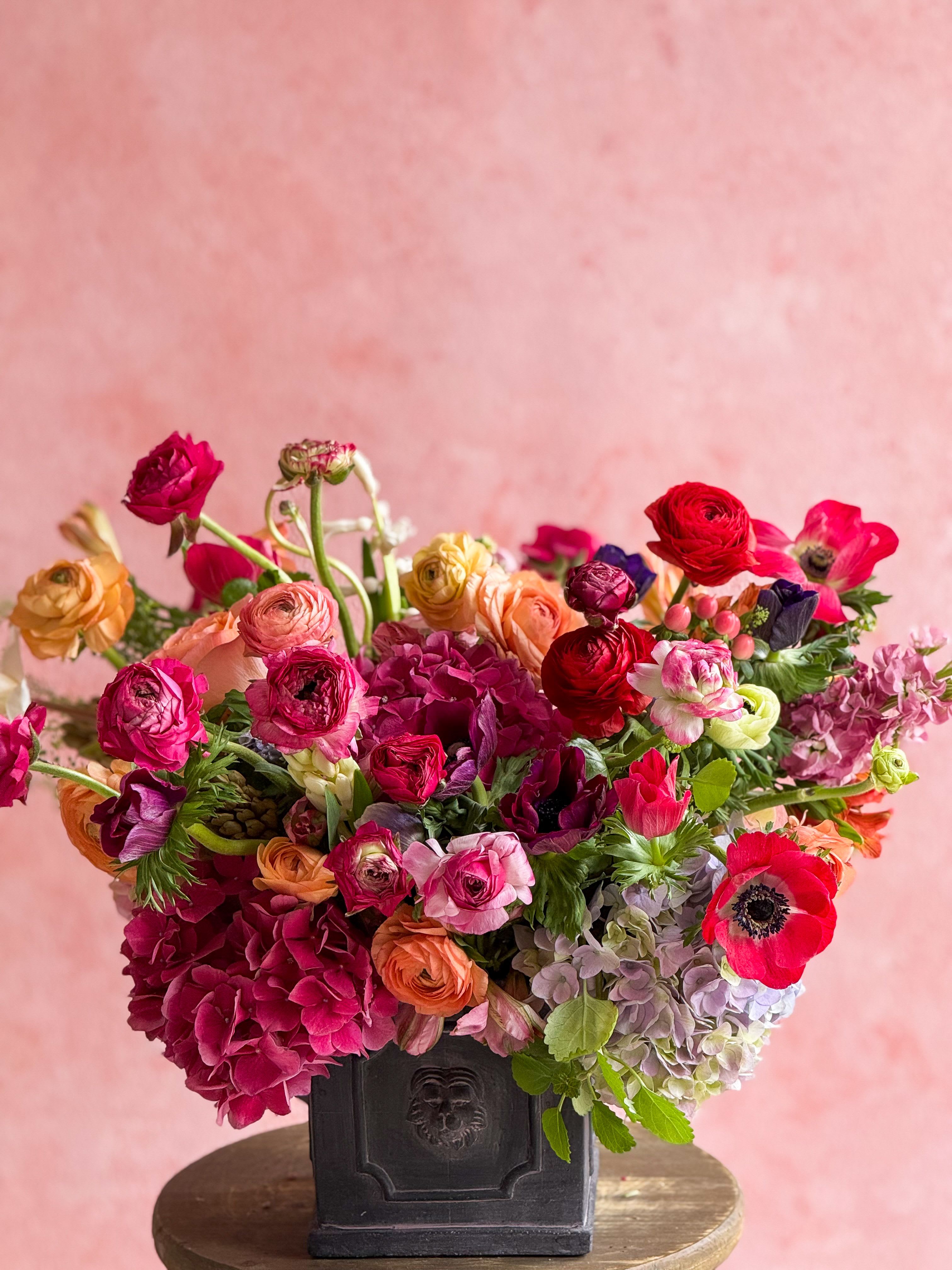 Colorful mixed flower arrangement in a dark vase