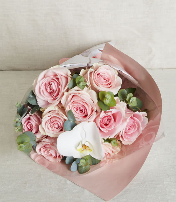 Bouquet of pink roses with a single white orchid wrapped in pink and clear paper