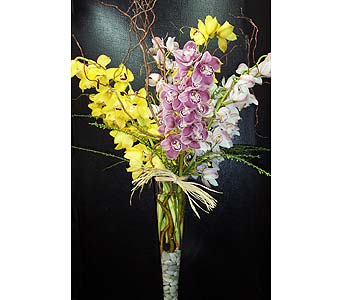 Tall bouquet of yellow, pink, and white orchids in a glass vase