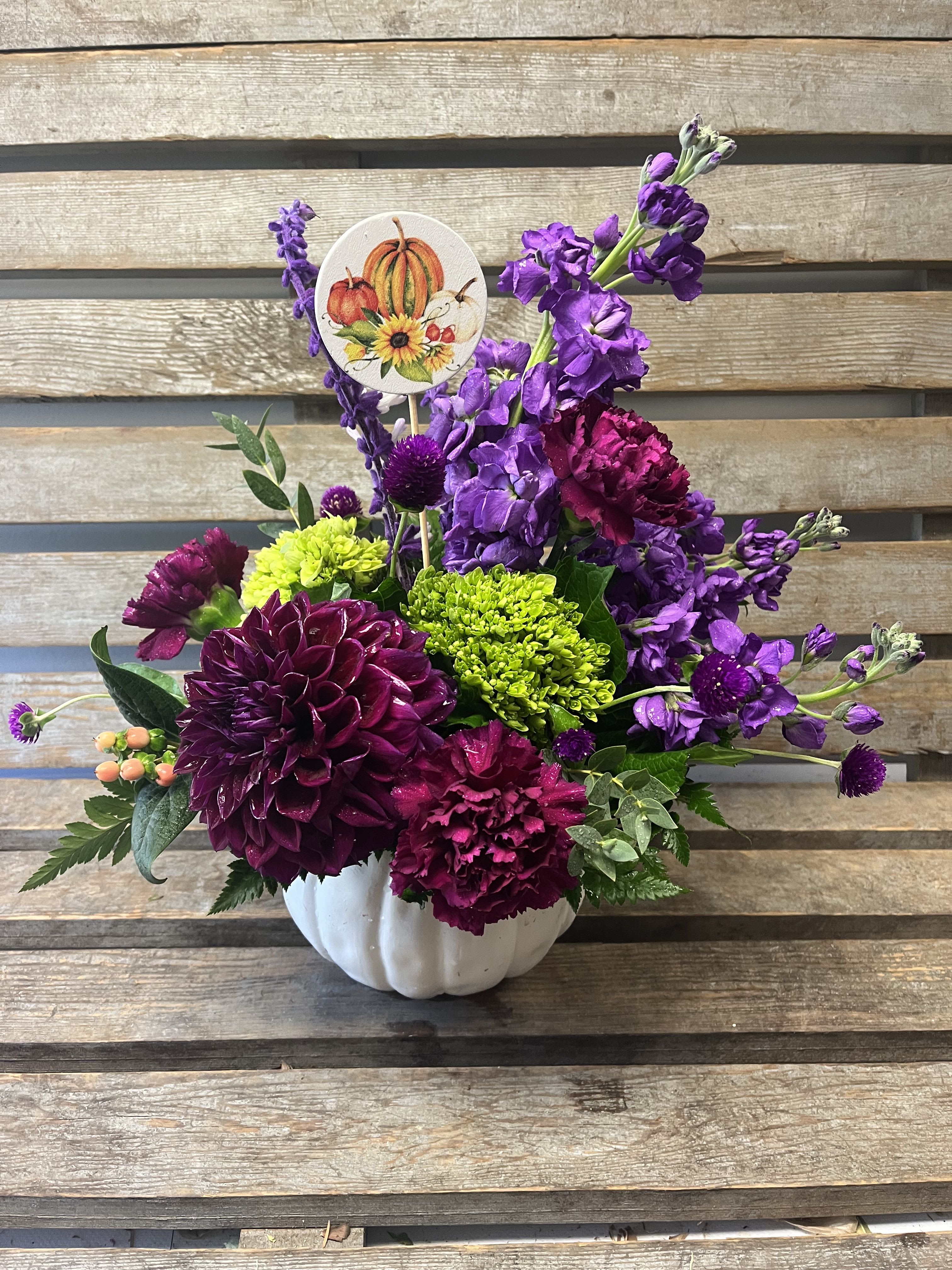 Purple and magenta floral arrangement in a white pumpkin vase