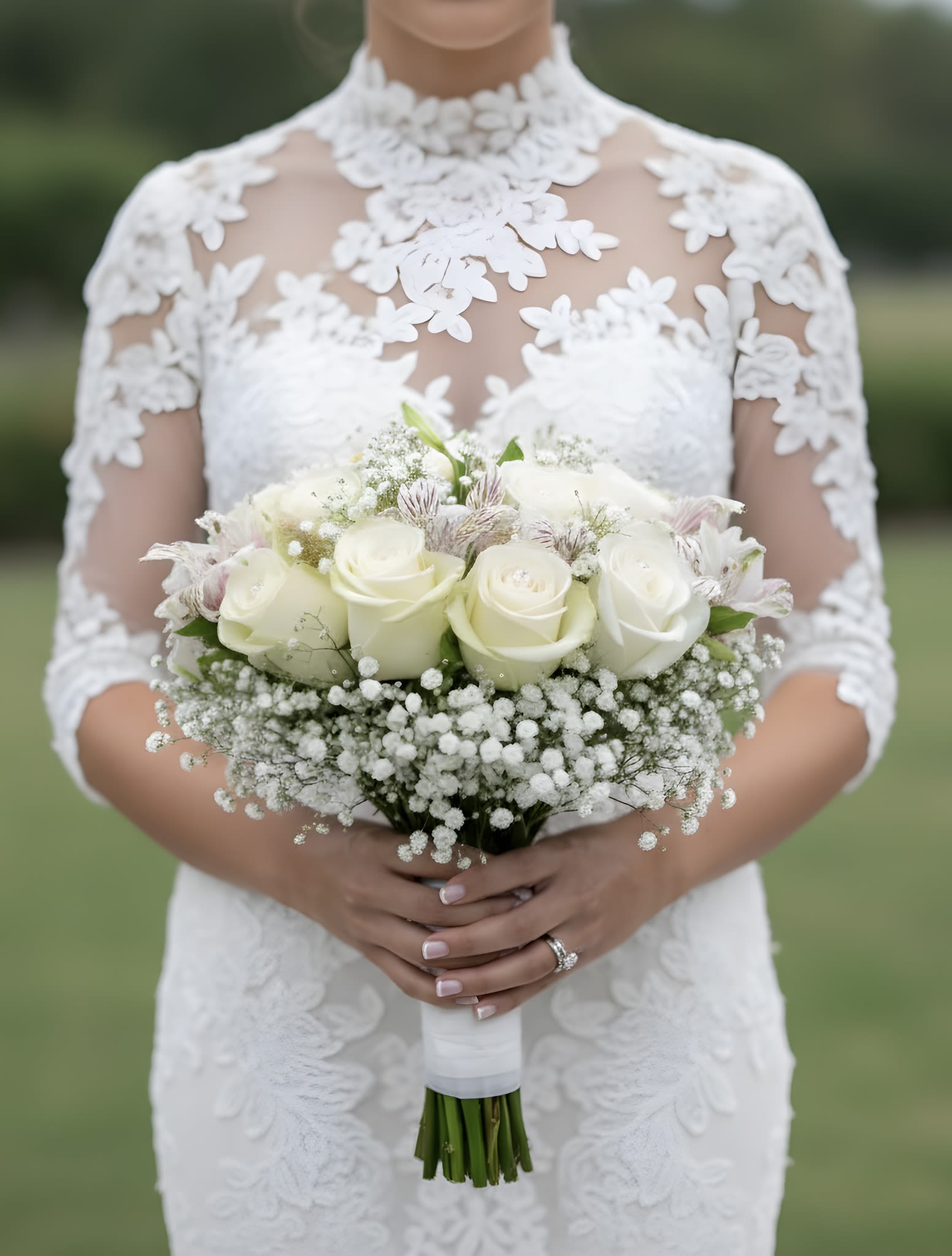 Bride holding a white rose bouquet with baby's breath