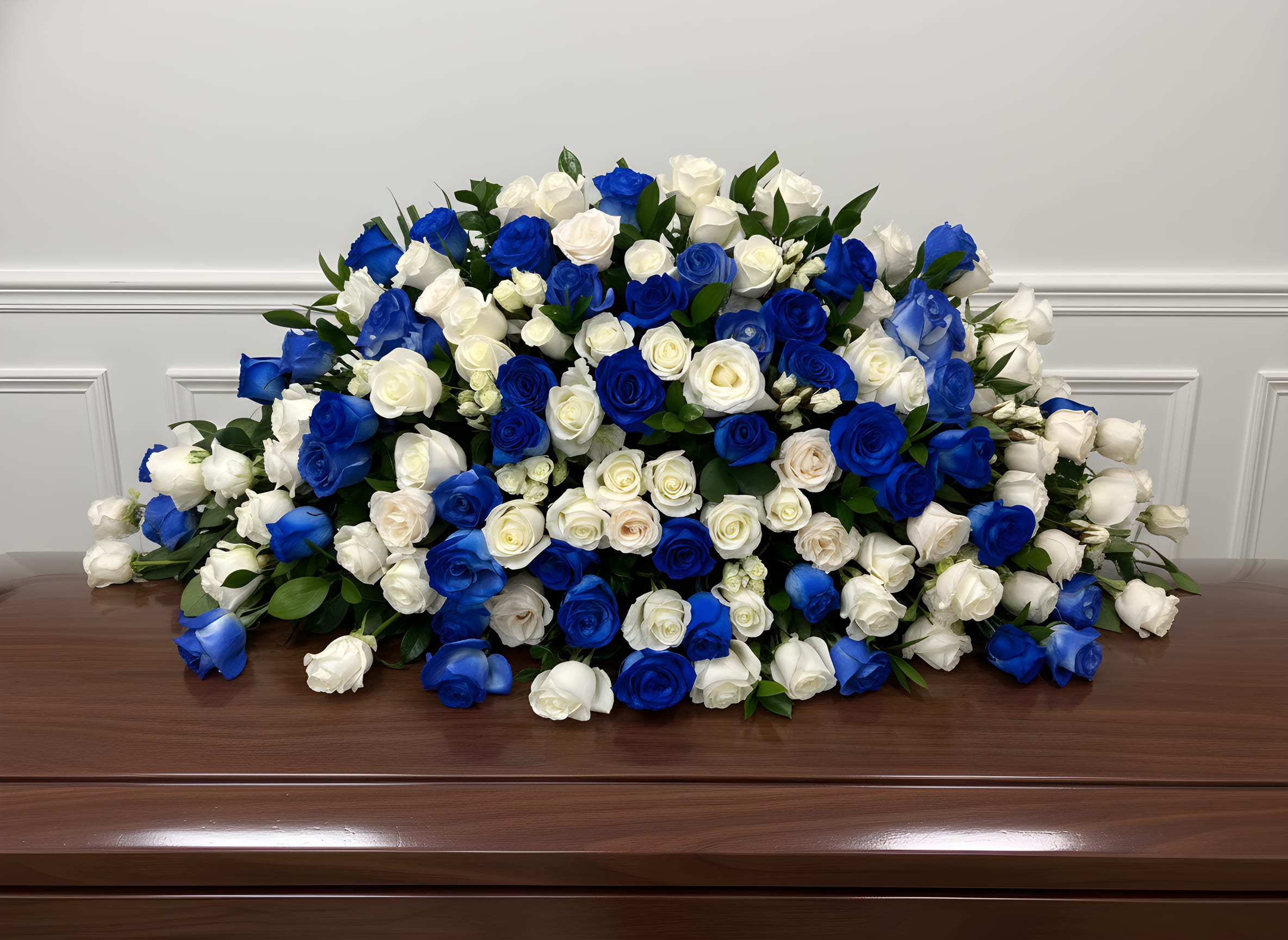 Large arrangement of blue and white roses on a wooden casket