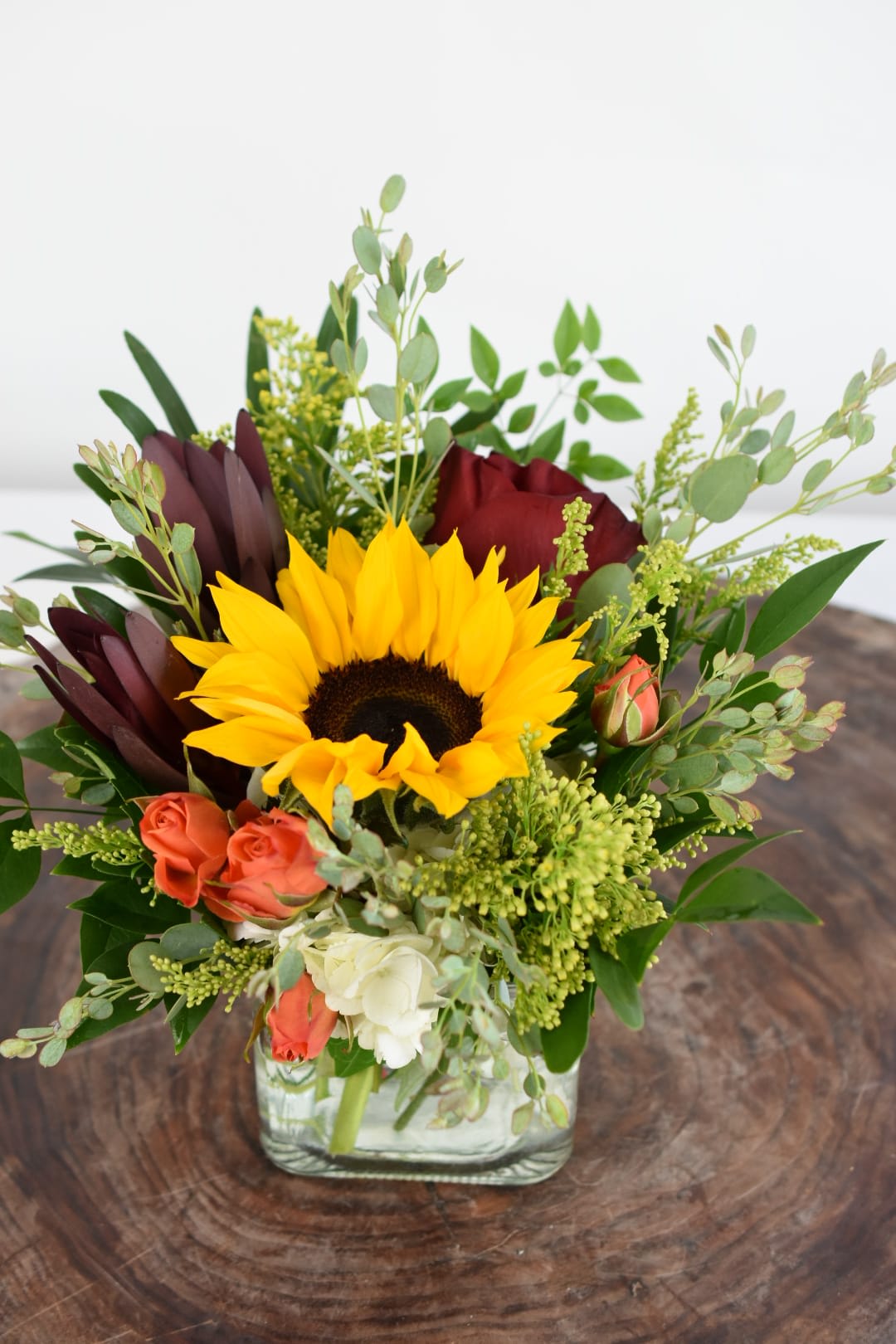 Sunflower and rose arrangement in a square glass vase