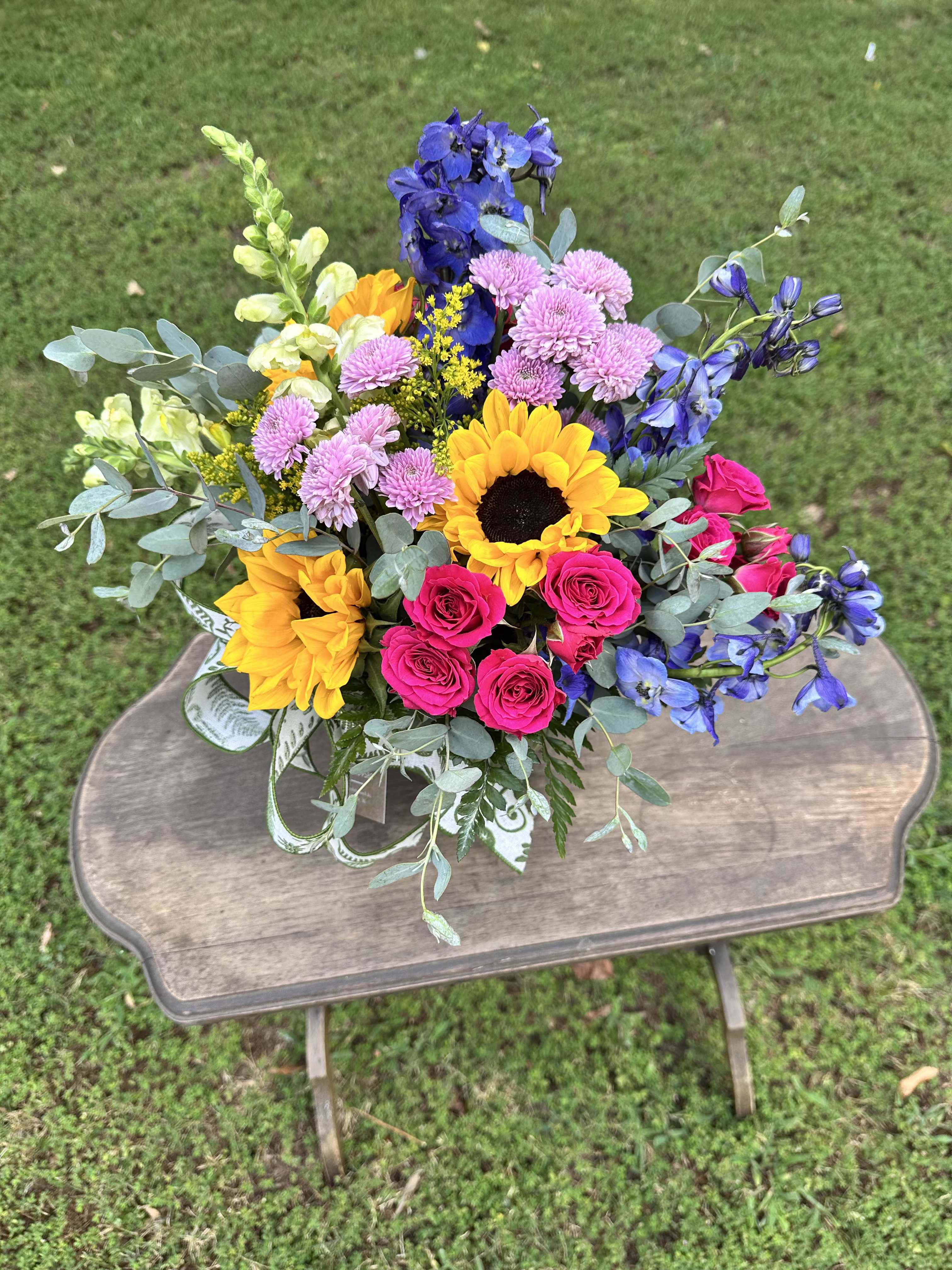 Just For You - A beautiful arrangement filled with sunflowers, blue delphinium, hot pink spray roses, white snapdragons, and lavender chrysanthemums.