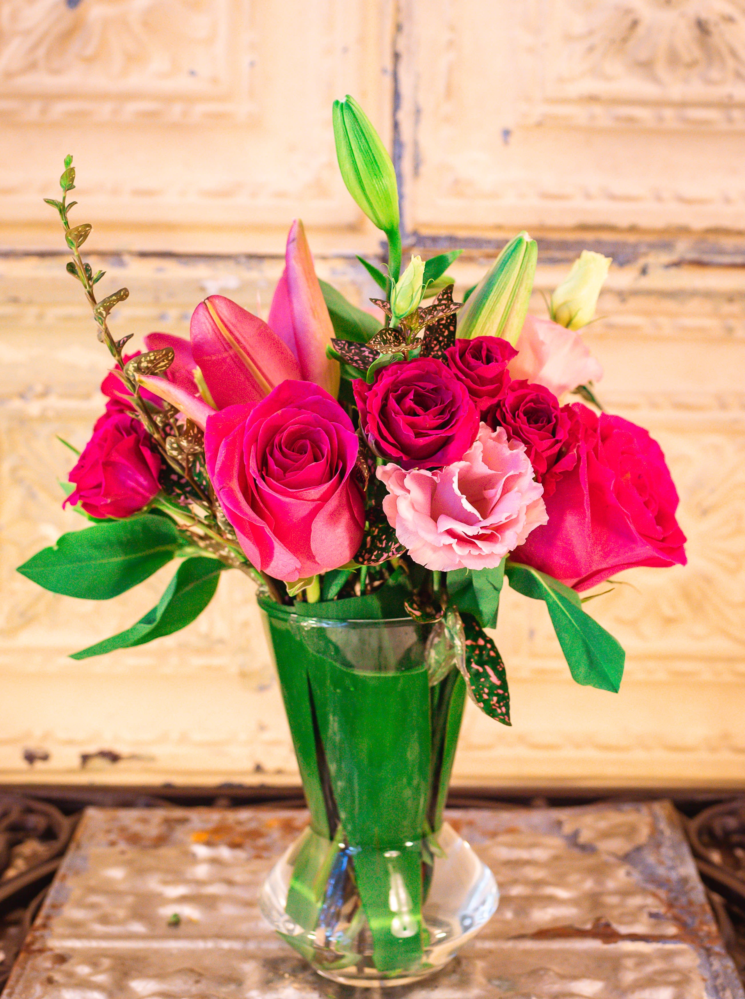 Pink roses and lilies arranged in a clear glass vase