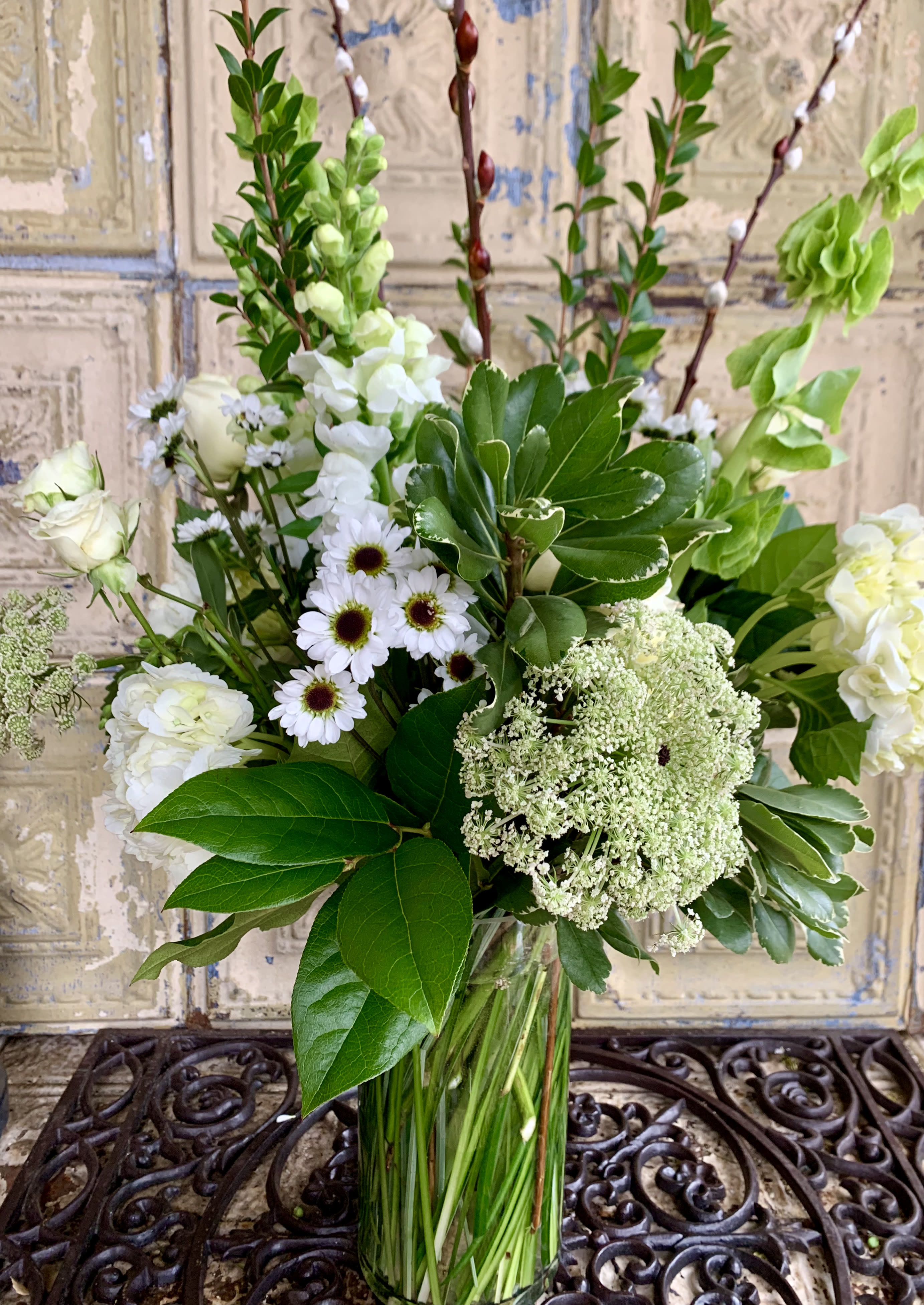 White flowers and greenery arranged in a clear glass vase