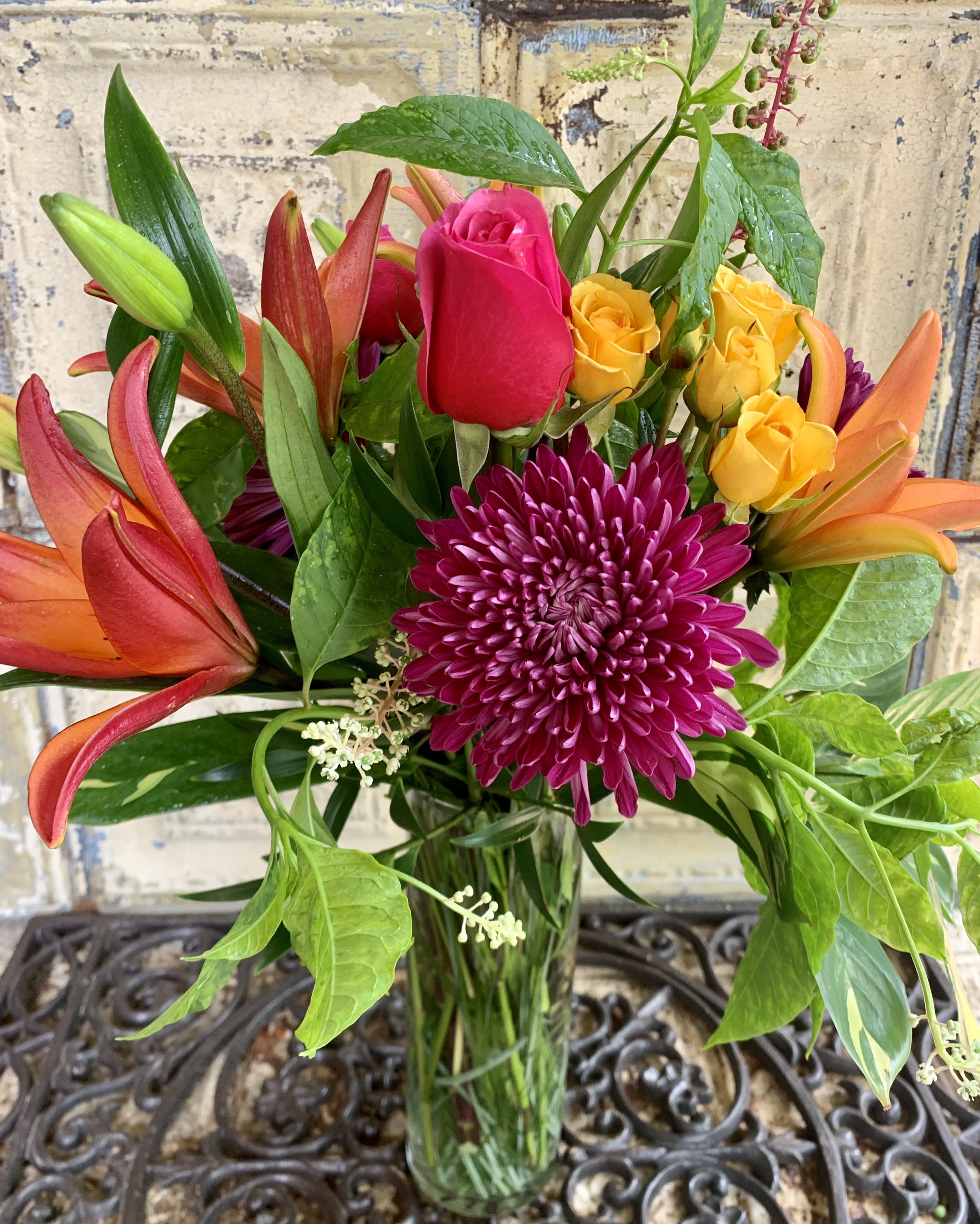 Bouquet of roses, lilies, and a chrysanthemum in a glass vase