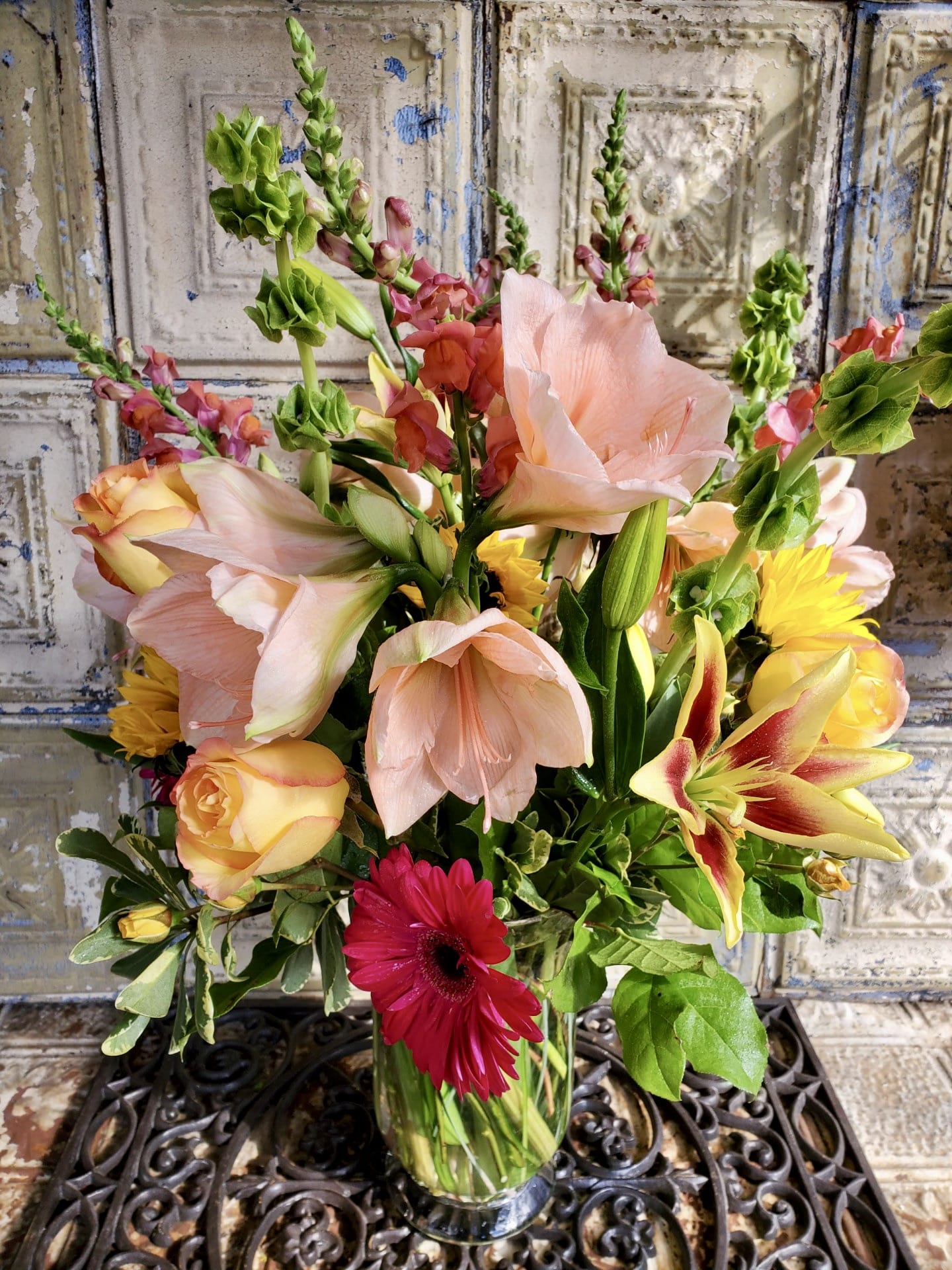 Mixed bouquet of lilies, roses, and a red gerbera daisy in a glass vase