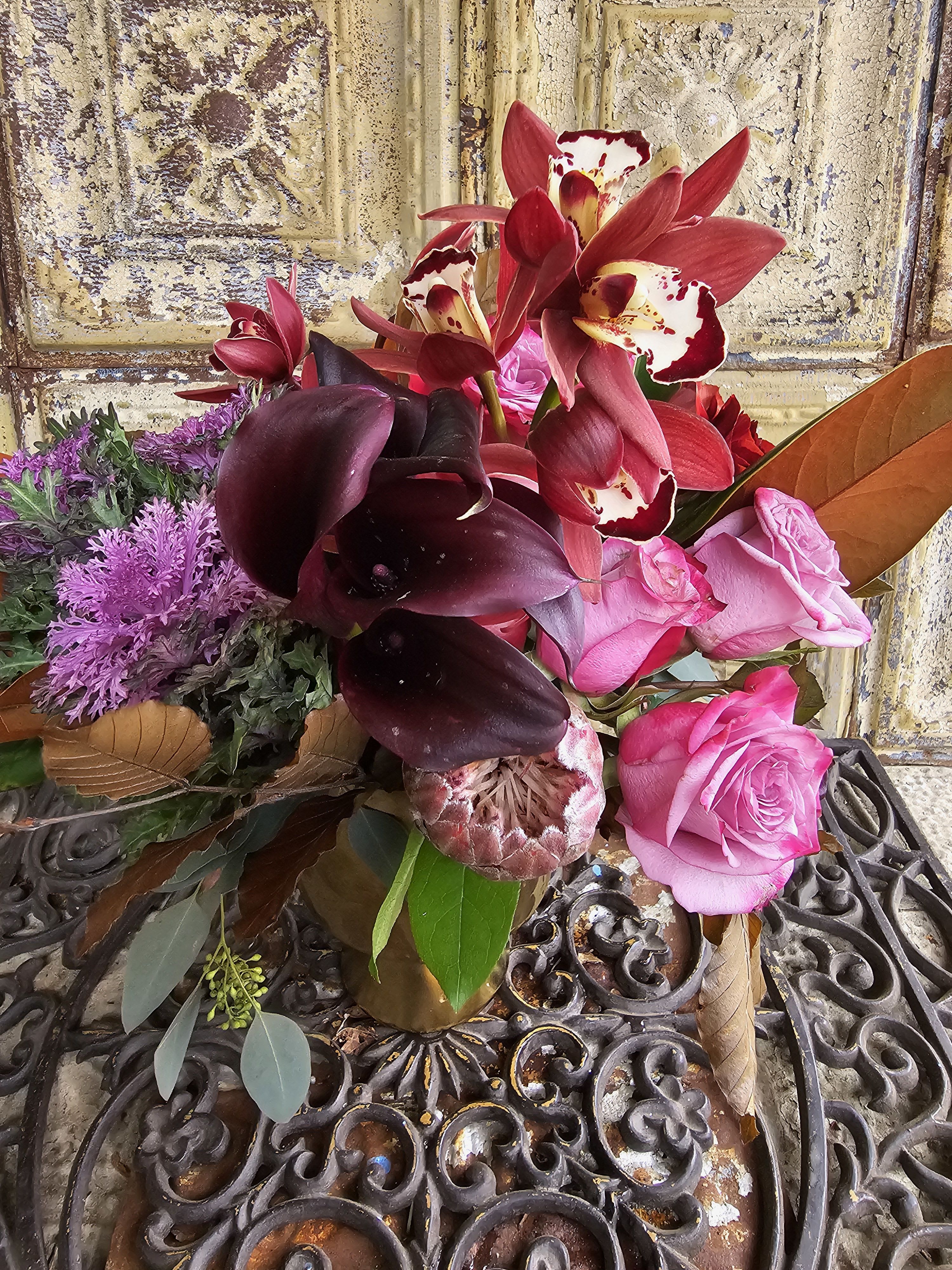 Bouquet of pink roses, dark calla lilies, and red orchids