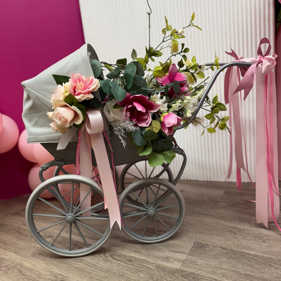 Floral arrangement in a gray baby carriage with pink ribbons