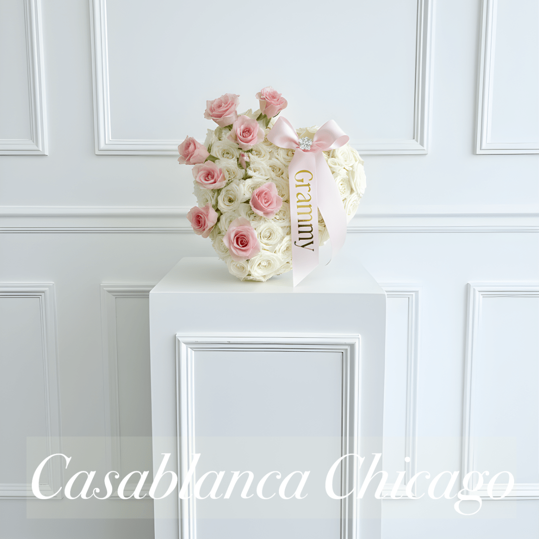 Pink and white rose arrangement with a pink ribbon on a pedestal