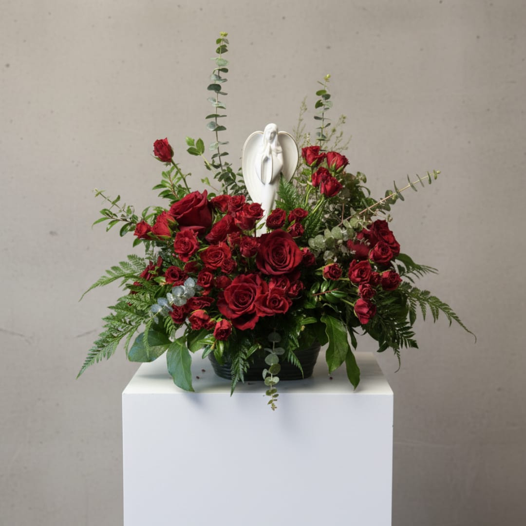 Red rose arrangement with a white angel figurine in a black container