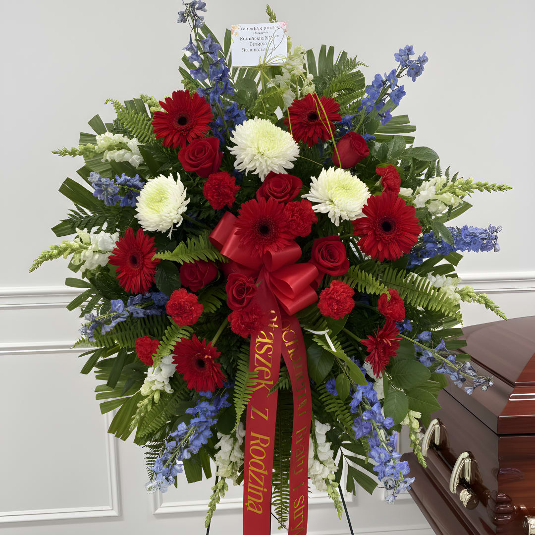 Large red, white, and blue funeral spray beside a casket