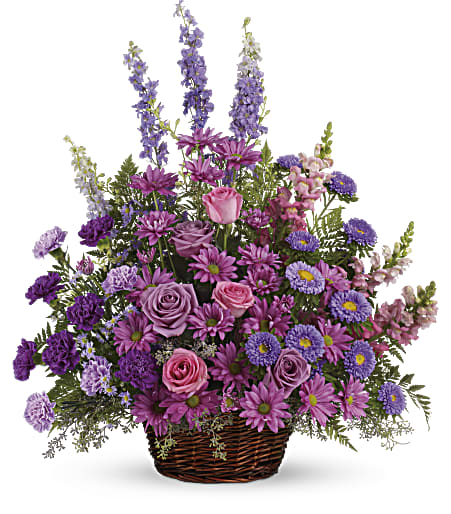 Purple and pink mixed flower arrangement in a wicker basket