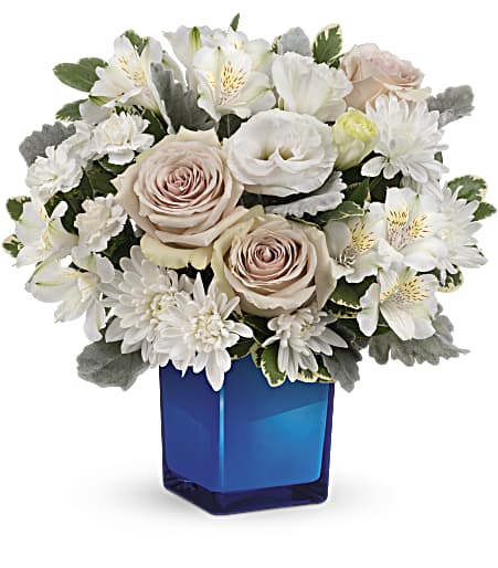 White and blush flowers arranged in a blue glass vase