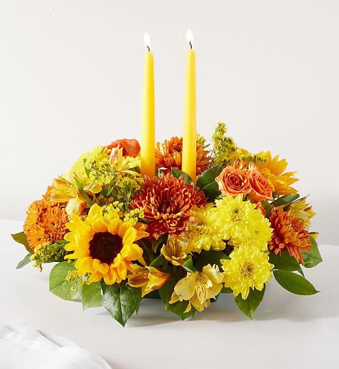 Yellow and orange floral centerpiece with two tall candles