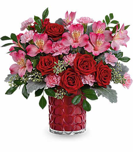Bouquet of red roses and pink alstroemeria in a red glass vase