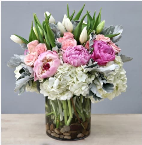 Pink and white flowers arranged in a glass vase with pebbles