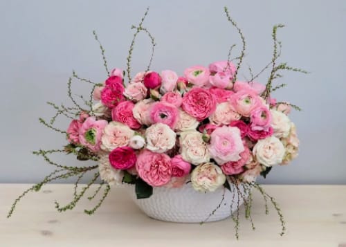Low centerpiece of pink and white blooms in a white ceramic bowl