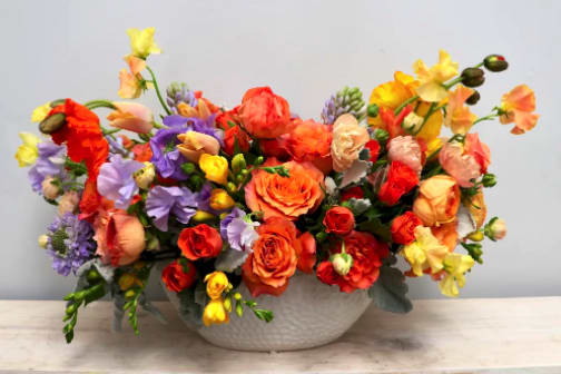 Colorful bouquet of mixed flowers in a white bowl vase