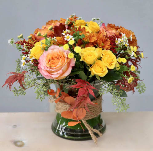 Autumn bouquet of roses and daisies in a glass vase