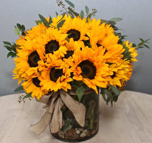 Bouquet of yellow sunflowers in a glass vase with a burlap ribbon