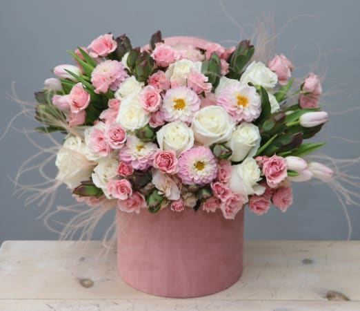 Round pink hatbox arrangement of soft pink and white roses, dahlias, carnations, and tulips