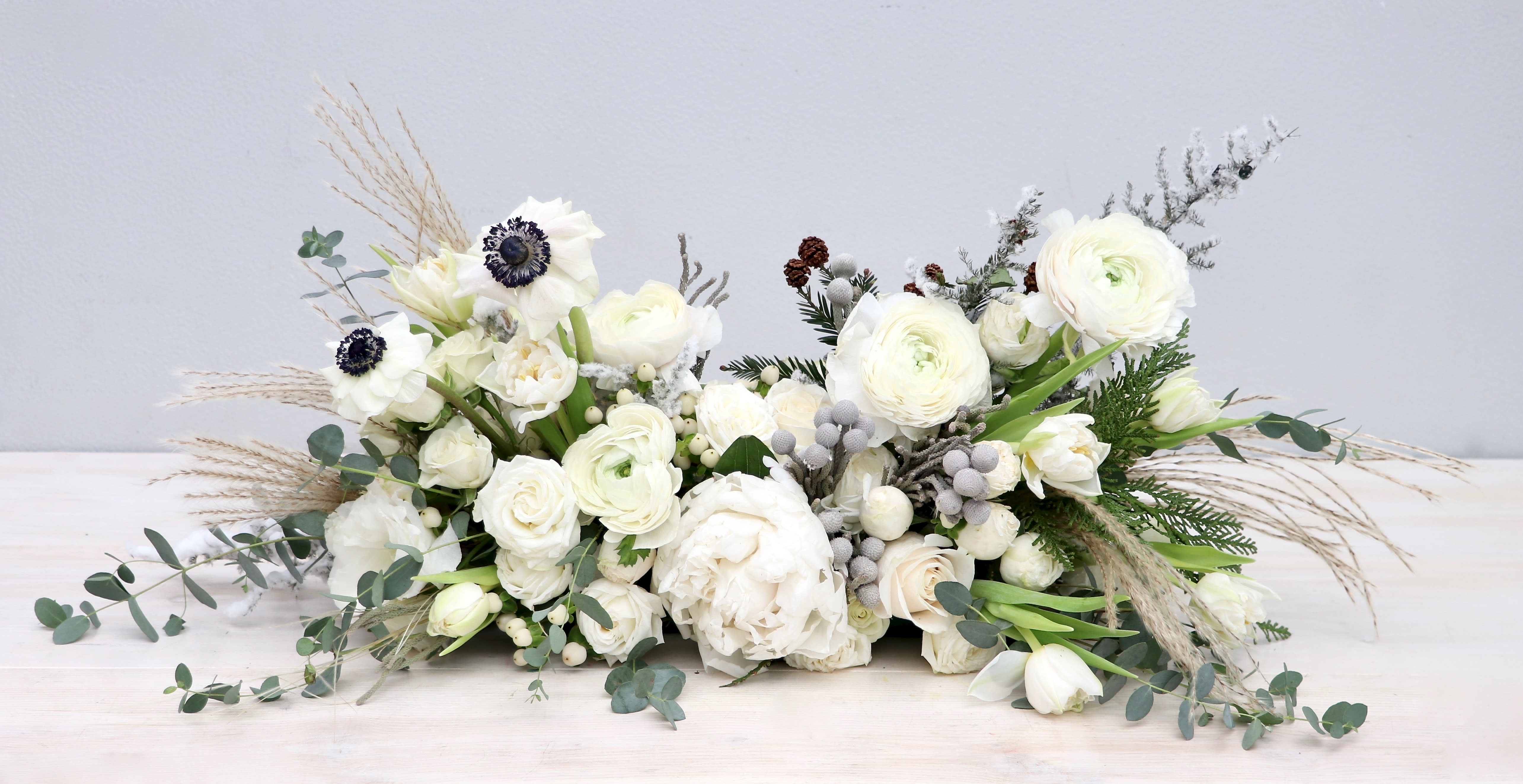 Low white floral arrangement with ranunculus and anemones
