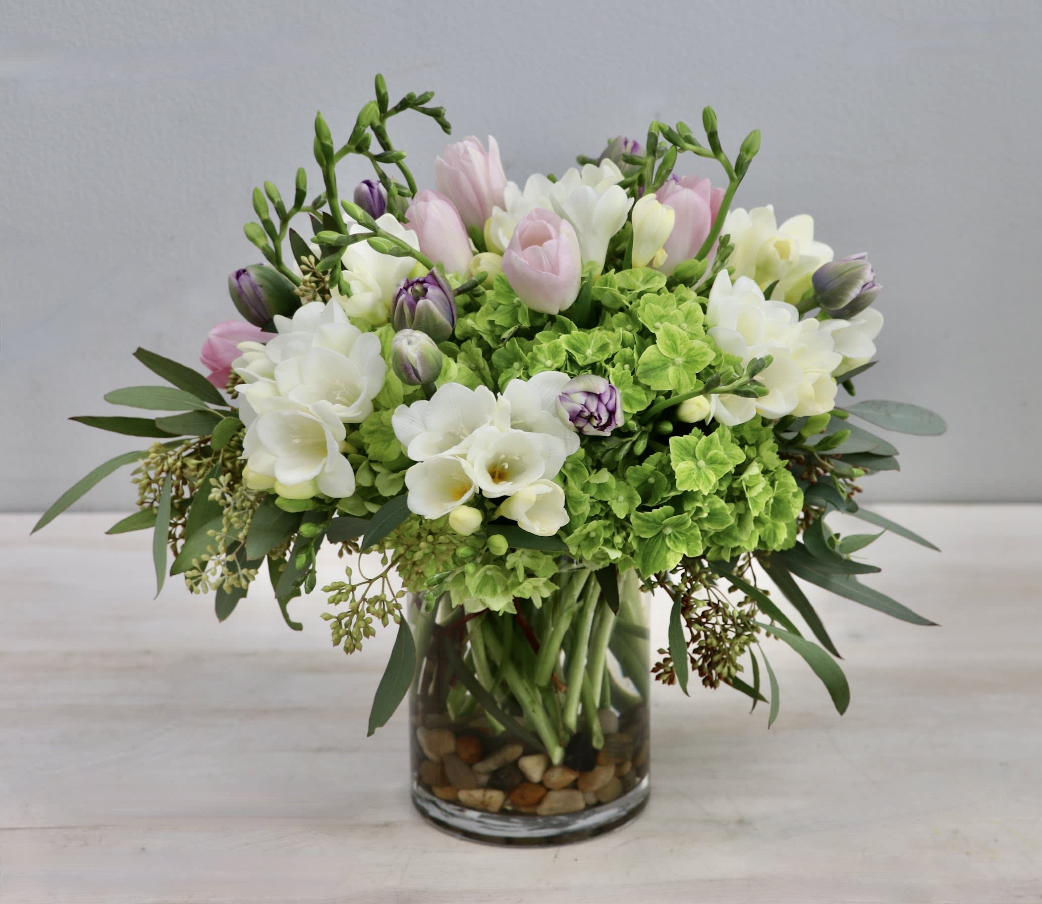 Pink and white flowers arranged in a glass vase with green blooms