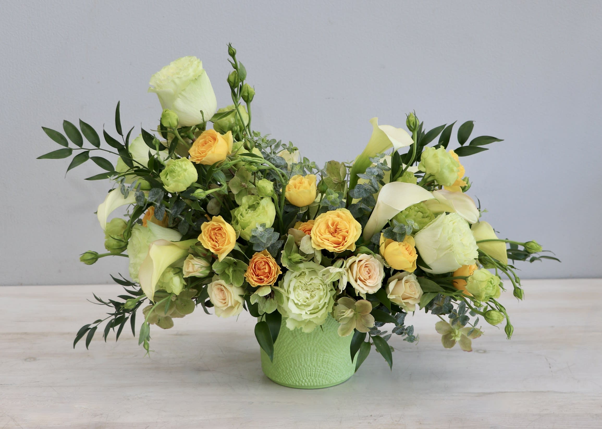 Lime Delight - WeHo - This zesty arrangement combines green tinted blooms with blush and yellow spray roses to create a vibrant and cheerful display. Roses, callas, lisianthus, and hellabore give this arrangement an amazing array of texture within a monochromatic pallet.