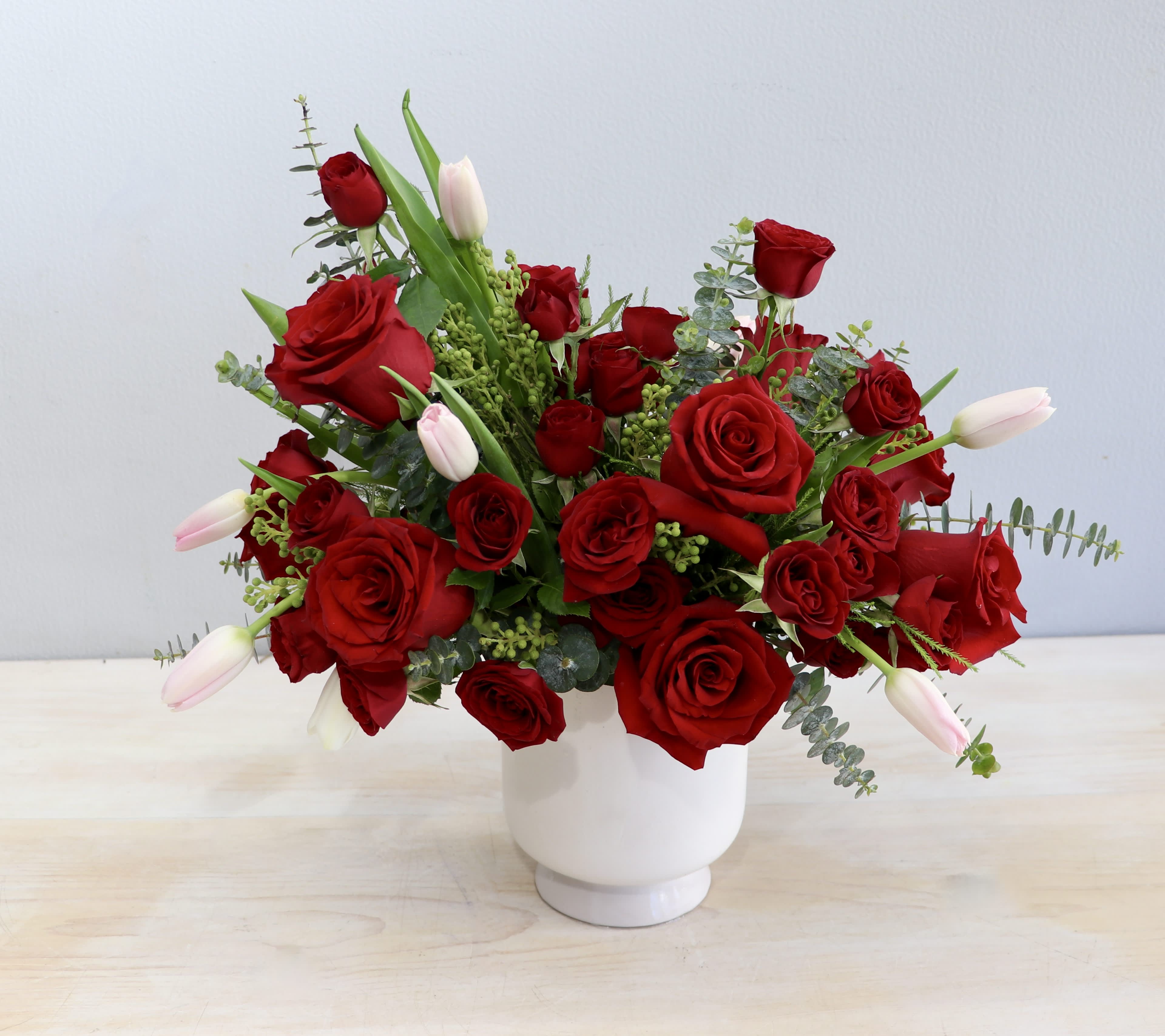 Red roses and pale tulips arranged in a white vase