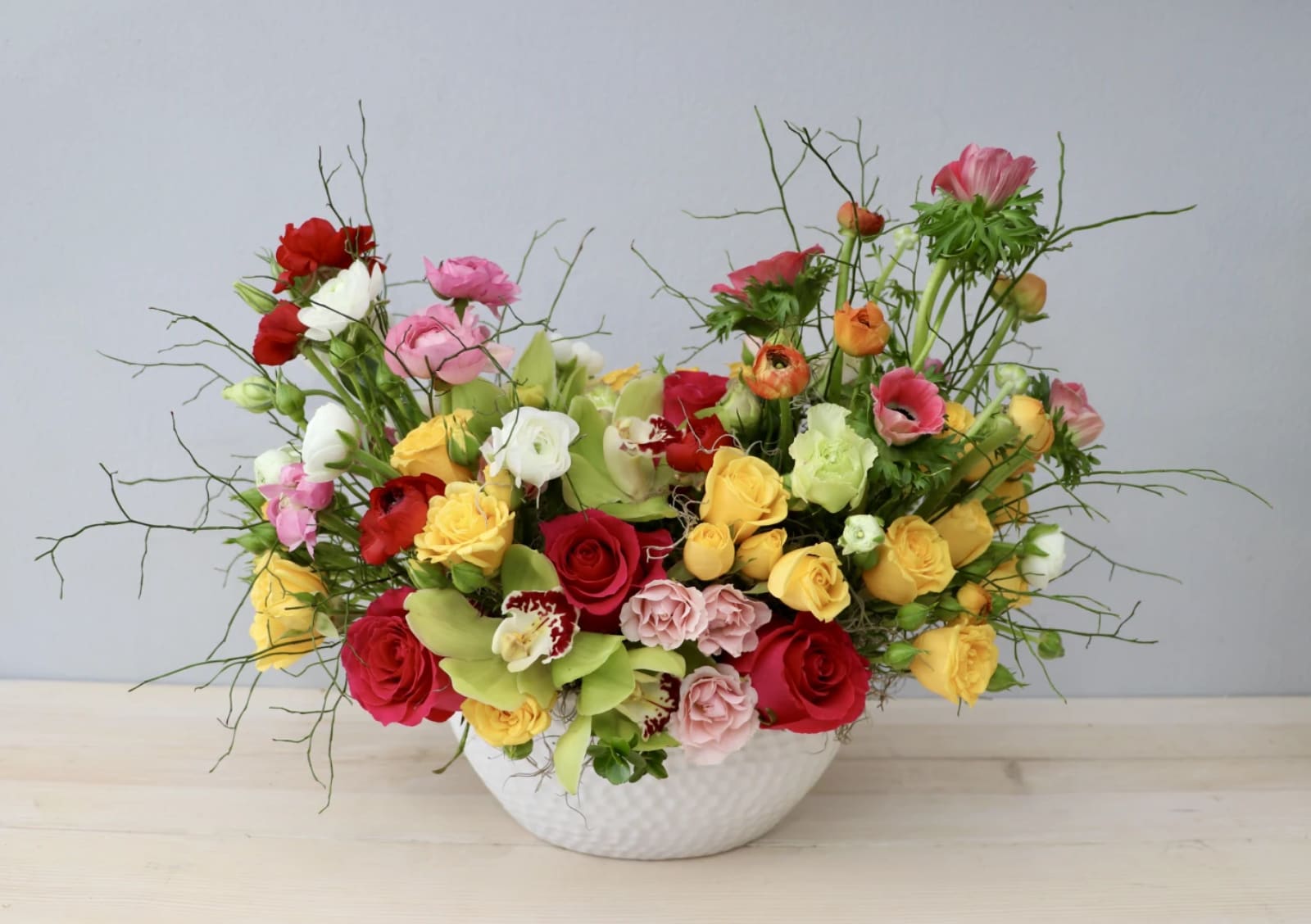 Mixed bouquet of roses and lisianthus in a white bowl vase